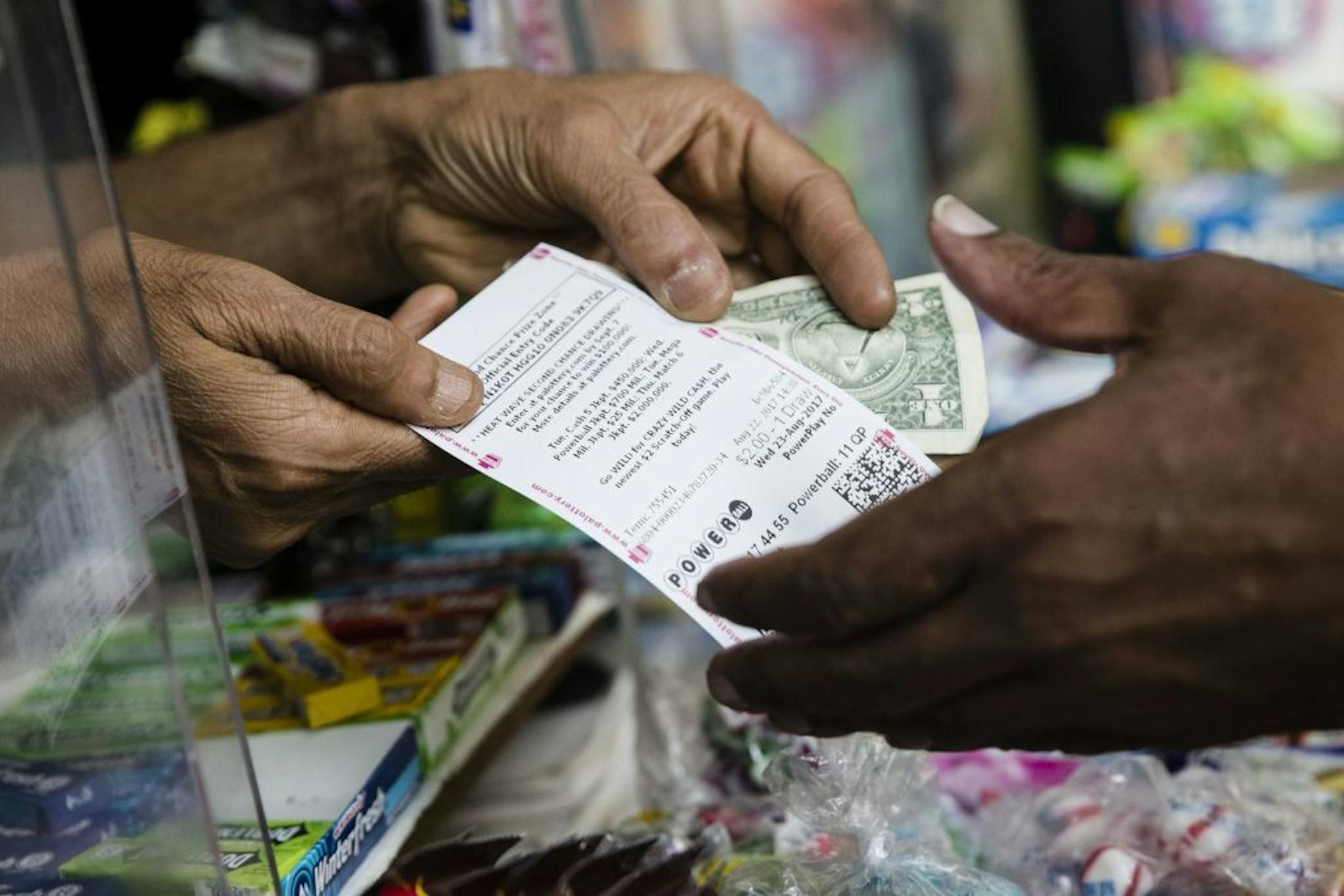 Atul Amin, left, sells a customer a Powerball ticket at his news stand in Philadelphia, Tuesday, Aug. 22, 2017.