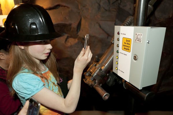 Katie Calger of Capitol Hill Magnet School in St. Paul uses a smart phone to "drill" in a mine exhibit at the Minnesota History Center earlier this ye