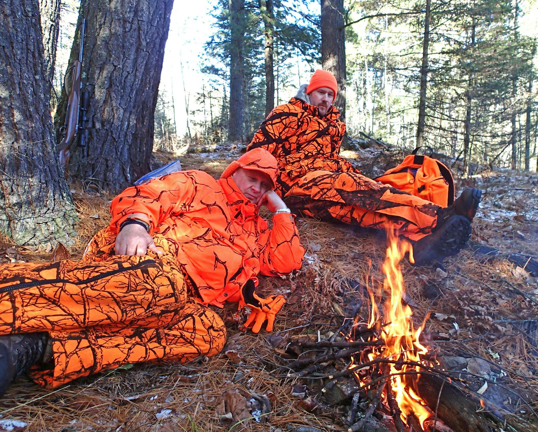 Lunchtime in the woods: Dick Anderson, left, and his son Brian, warm up by a noontime campfire on the opening day of deer season. Whitetail sightings were rare in northeast Minnesota on opening weekend.
