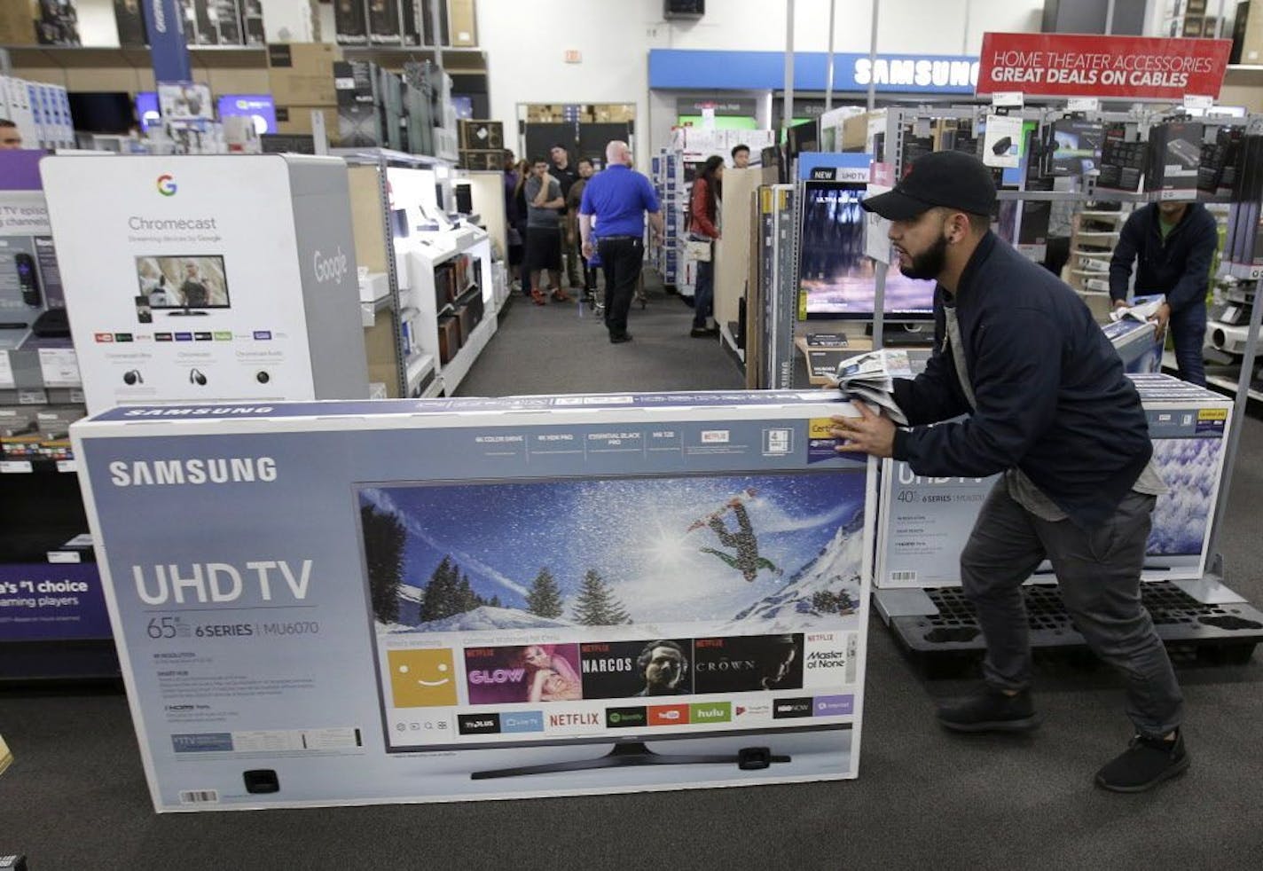 FILE - In this Nov. 23, 2017, file photo, Jesus Reyes pushes a television down an aisle as he shops at a Black Friday sale at a Best Buy store in Overland Park, Kan. On Wednesday, Feb. 14, 2018, the Commerce Department releases U.S. retail sales data for January.