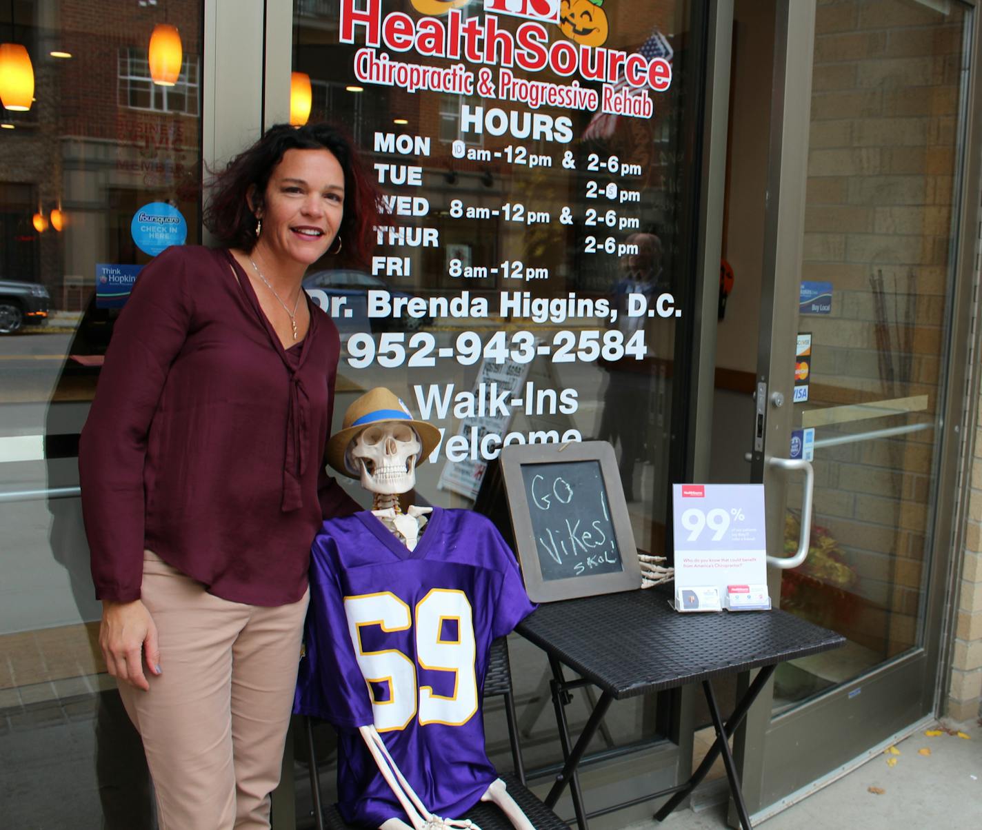 Brenda Higgins, owner of HealthSource Chiropractic in Hopkins, poses next to "Lux," a skeleton aimed at attracting attention to her business on Mainstreet.