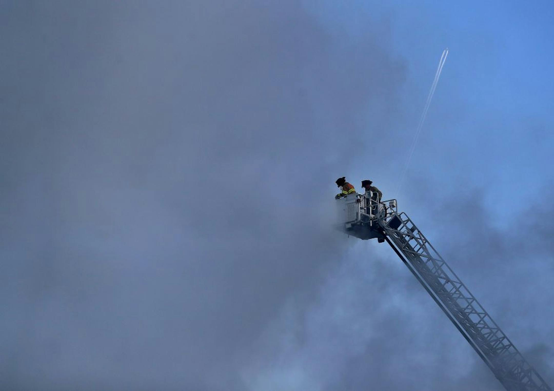 Fire ripped through a $69 million project hotel/apartment project early Tuesday morning, causing massive damage near the Xcel Energy Center in St. Paul. Here, St. Paul firefighters put water on the fire as a plane flies in the morning sky.