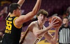 Minnesota center Liam Robbins eyed the basket as Iowa center Luka Garza defended in the first half Dec. 25. 