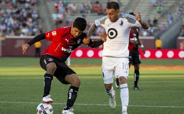 Atlas' Luis Robles maintains control over the ball against Minnesota United's Miguel Ibarra during the first half of an international friendly soccer 