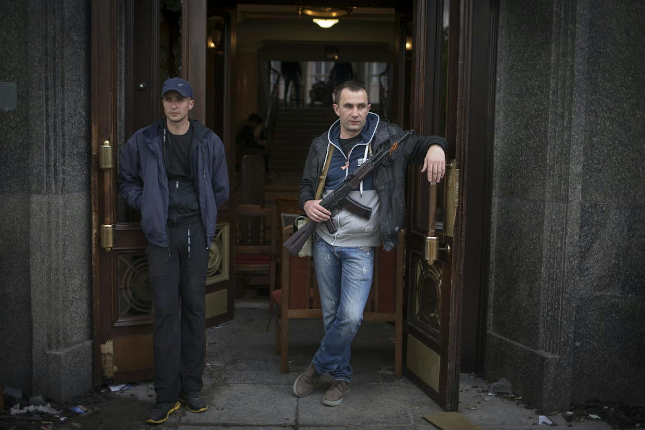 April 29, 2014: Pro-Russian activists, one of them holds a Kalashnikov gun, as they guard an entrance to the captured administration building in the center of Luhansk, Ukraine.