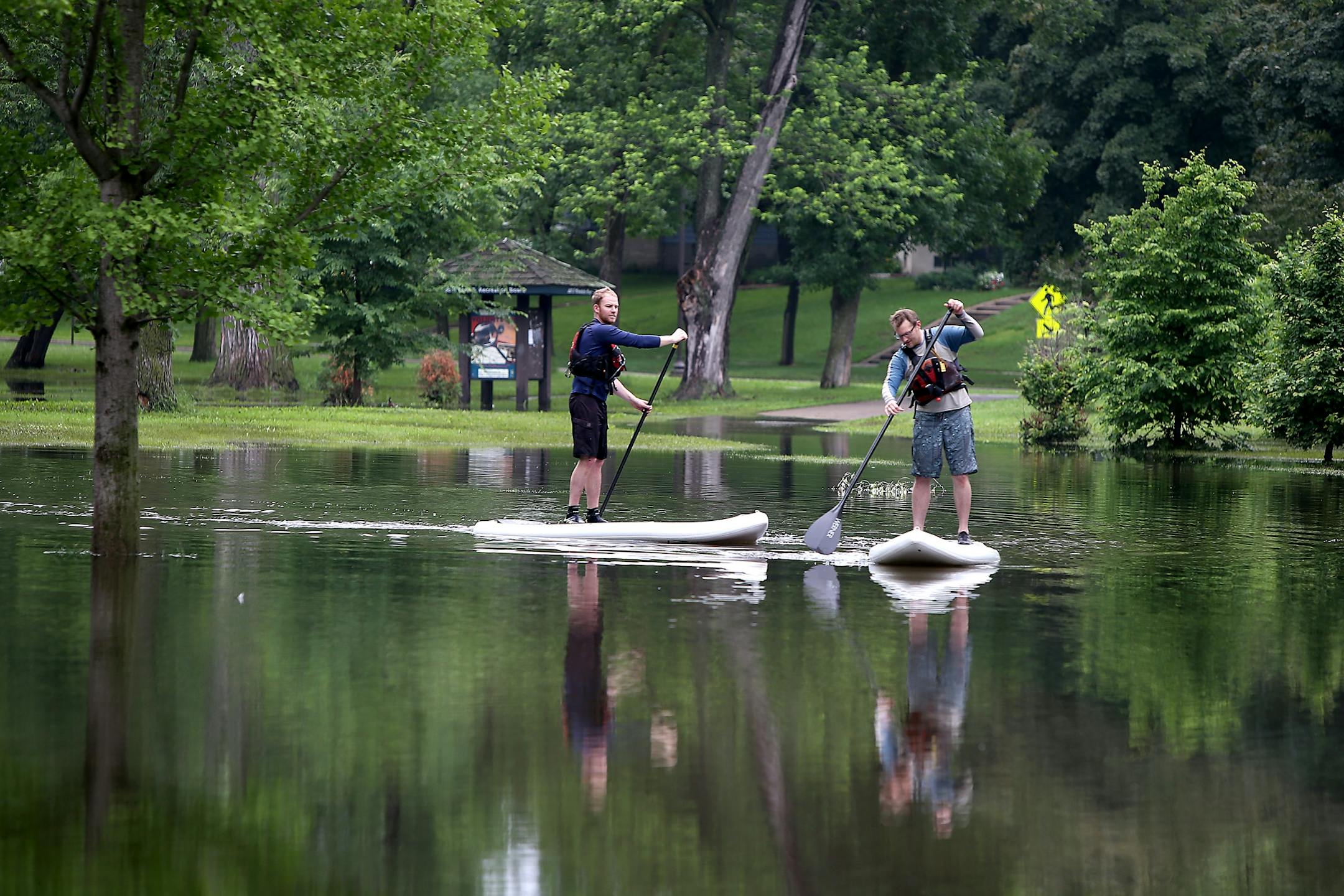 Ryan Welty, left, and JB Matthews made their way across the flooded Minnehaha Parkway on a stand-up paddle board, Friday, June 20, 2014 in Minneapolis, MN.
