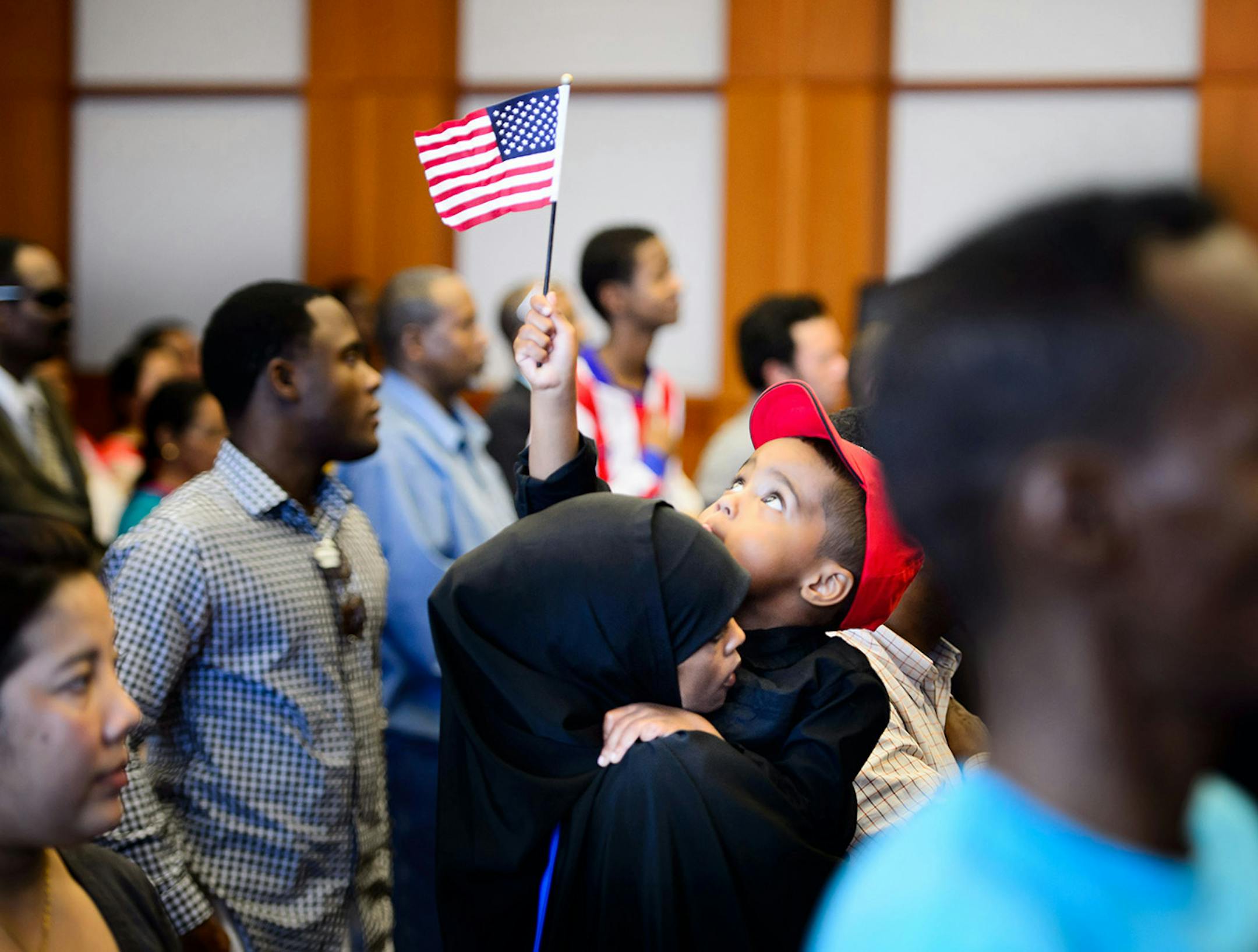 Ayuub Muse, 3, waved a flag as his mom Amina Yusuf, left, became a U.S. citizen.