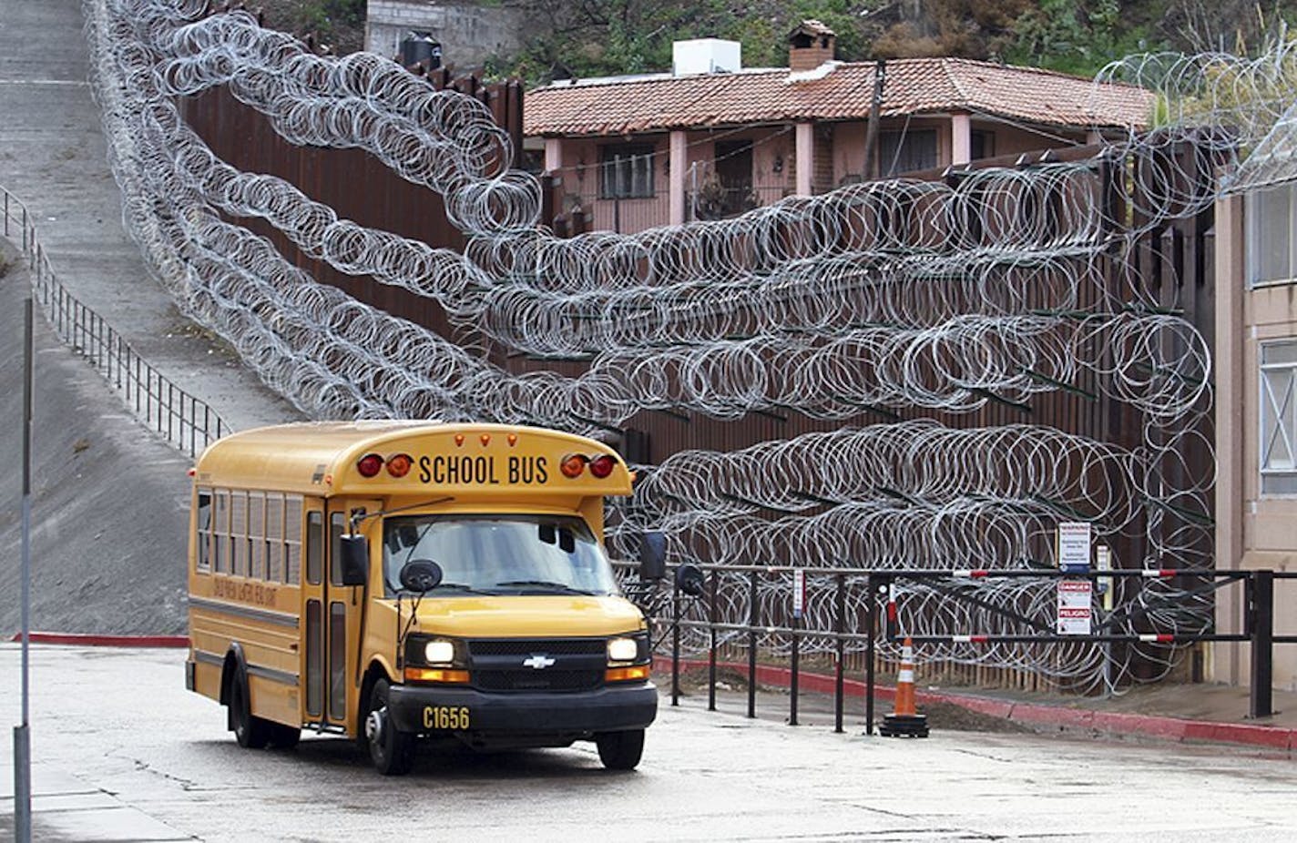 In this Monday, Feb. 4, 2019 photo, a school bus rolls past the concertina wire-covered fence at East International and Nelson Streets in downtown Nogales, Ariz. The small Arizona border city is fighting back against the installation of razor fencing that now covers the entirety of a tall border fence along the city's downtown area. The city of Nogales, which sits on the border with Nogales, Mexico, is contemplating a proclamation Wednesday, Feb. 6, 2019, condemning the use of concertina wire in