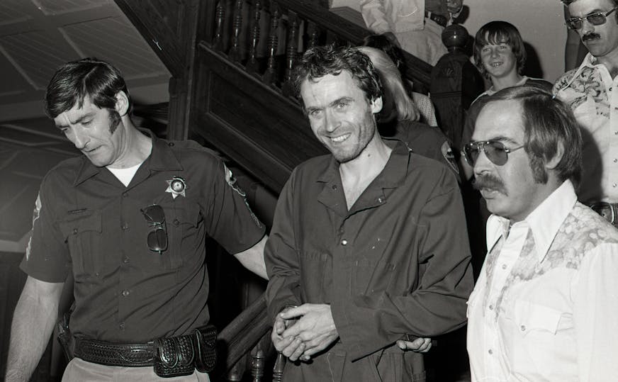 black and white photo of two officers arresting Ted Bundy
