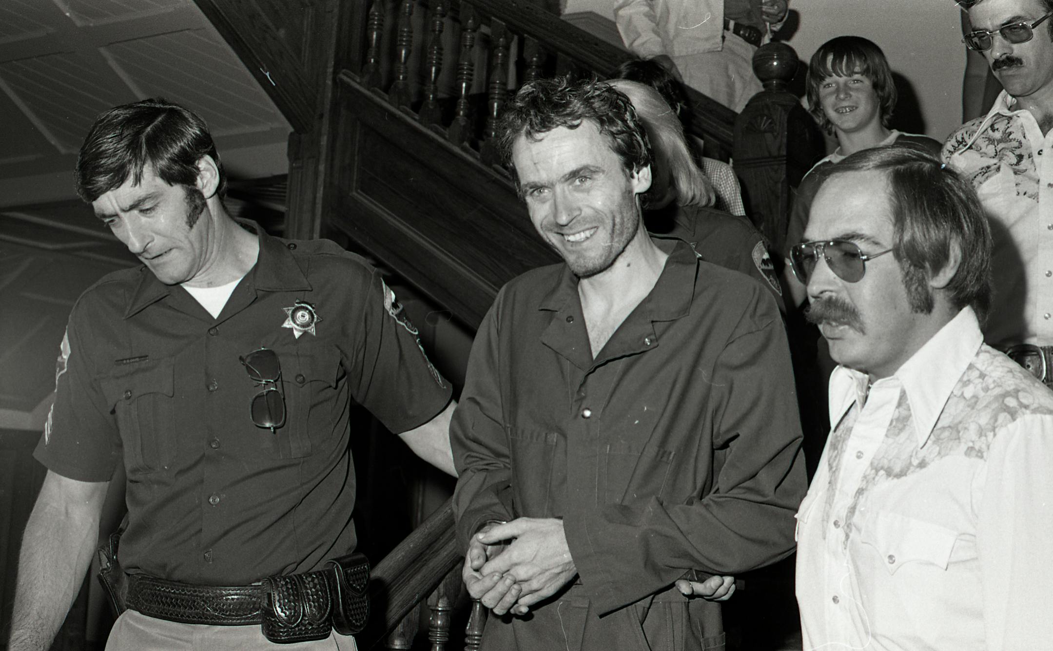 black and white photo of two officers arresting Ted Bundy