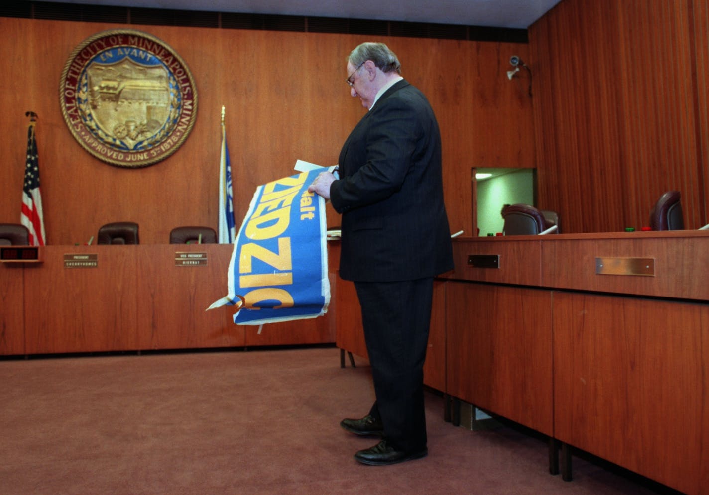 long time city council members dziedzic, rainville and shulstad retire ( also scott) -- era.15435 -end of an era, Walt Dziedzic, one of the three longest serving council members who retired today, removed his name plate from in front of his seat, and an old campaign banner that had been taped to the front of the desk, as he left the city council chambers to join family and friends for a reception after the 3 1/2 hr mtg.