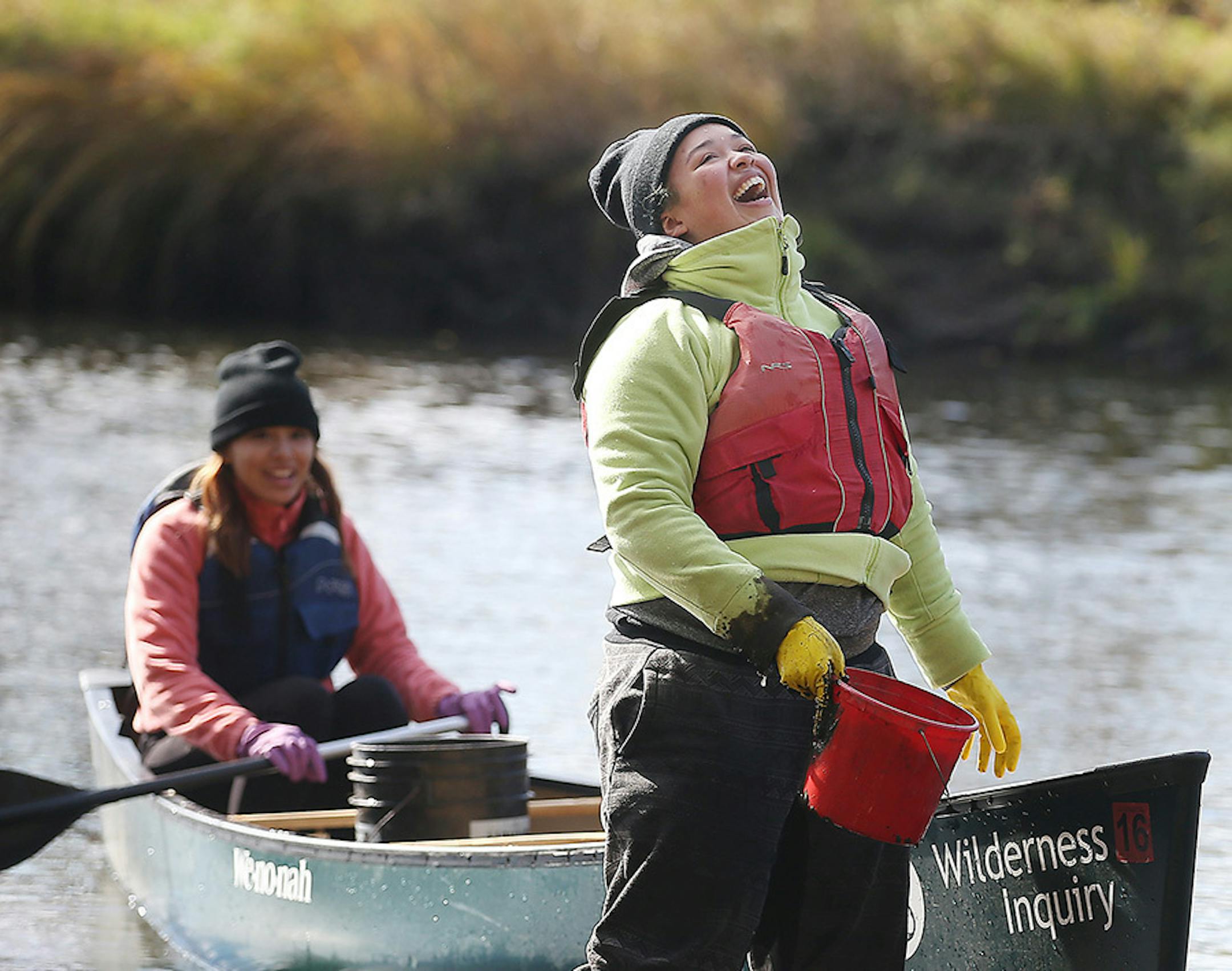 Haley Woodard laughed as she got stuck in the mud as classmate Gabby Moose held the canoe, as they planted wild rice seeds along the Rum River, Tuesday, October 13, 2015 near Cambridge, MN.