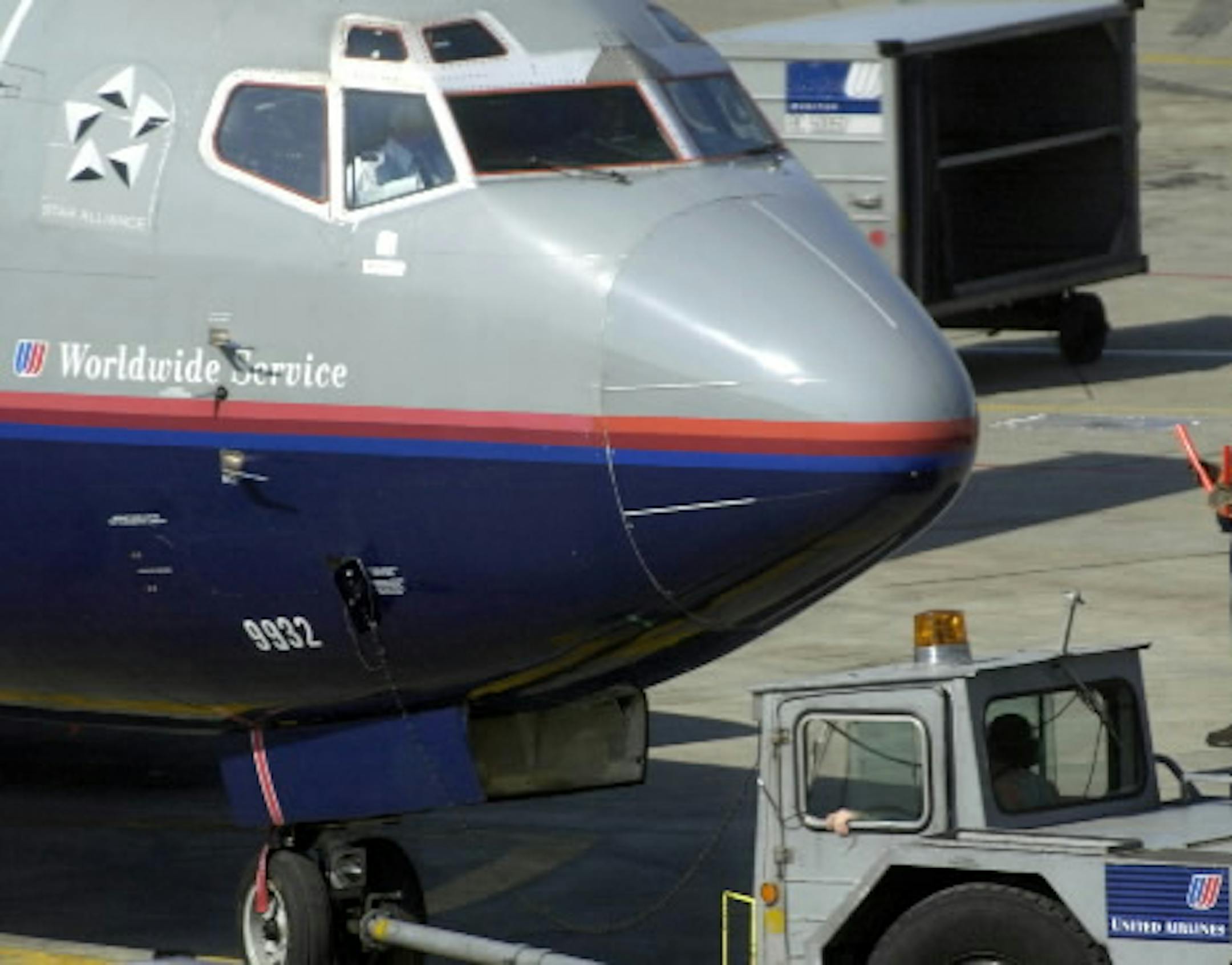 A United Airlines employee signals the flight crew as a plane is pushed back from the gate at O'Hare International Airport on Friday, April 11, 2003 in Chicago, Illinois. United has reached agreement with its mechanics' union on a six-year contract that would cut hourly wage rates 13 percent, raise medical insurance co-payments for employees and change work rules, saving the airline $2.09 billion while preserving pensions, vacations and holidays, the union said. Photographer: TannenMaury/Bloombe