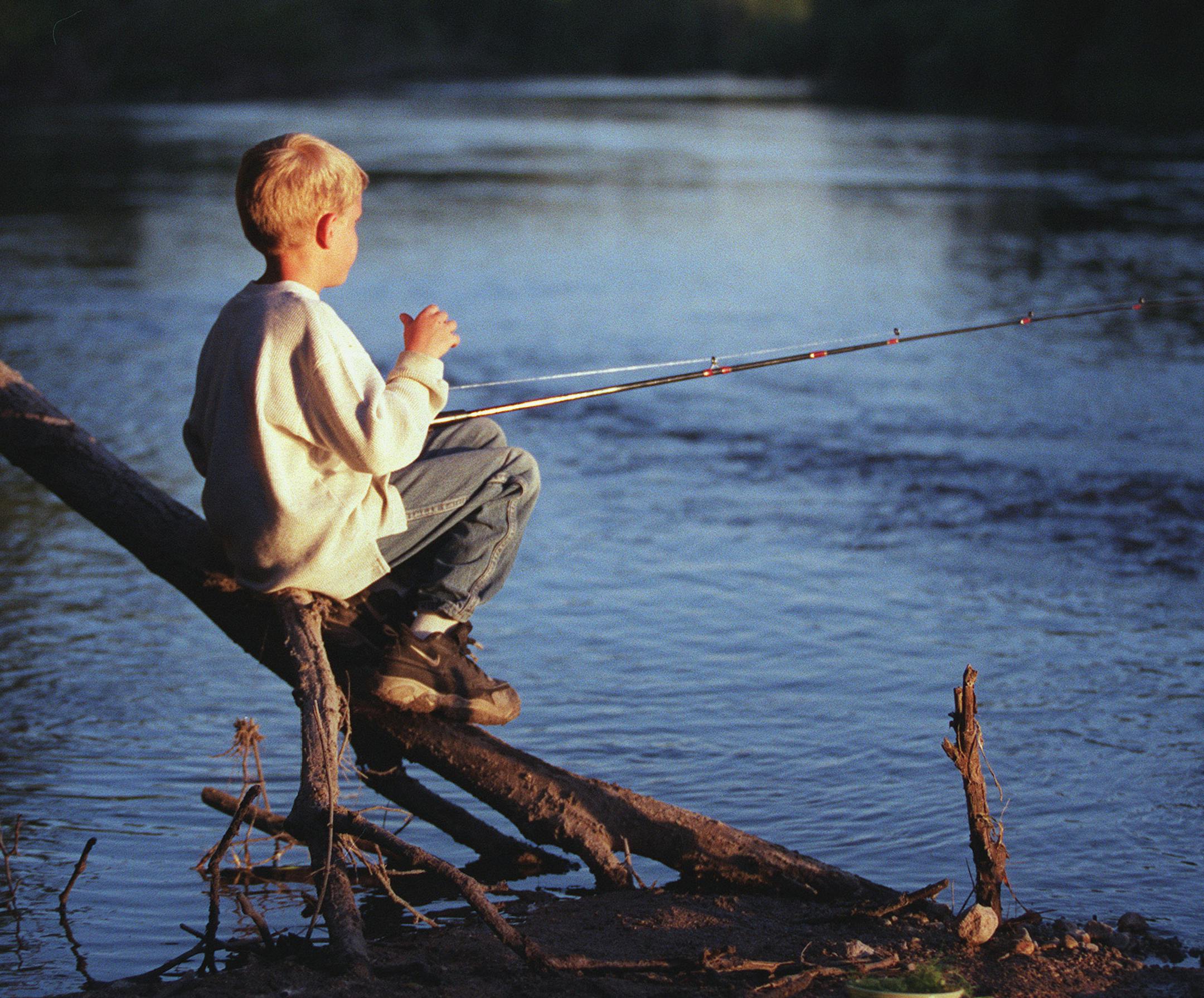 With his butter tub full of bait, 7-year-old Logan Kopischke of Franklin, MN perches on a deadfall fishing for catfish at his secret fishing hole on the Minnesota River. (507-249-2120) ÏThe Minnesota river can be restored, but not without considerable work. It should be a place where you slow down and look at life and listen to life.Ó - Del Wehrspann cattle buyer and river activist from Montevideo. ORG XMIT: MIN2012121723151984