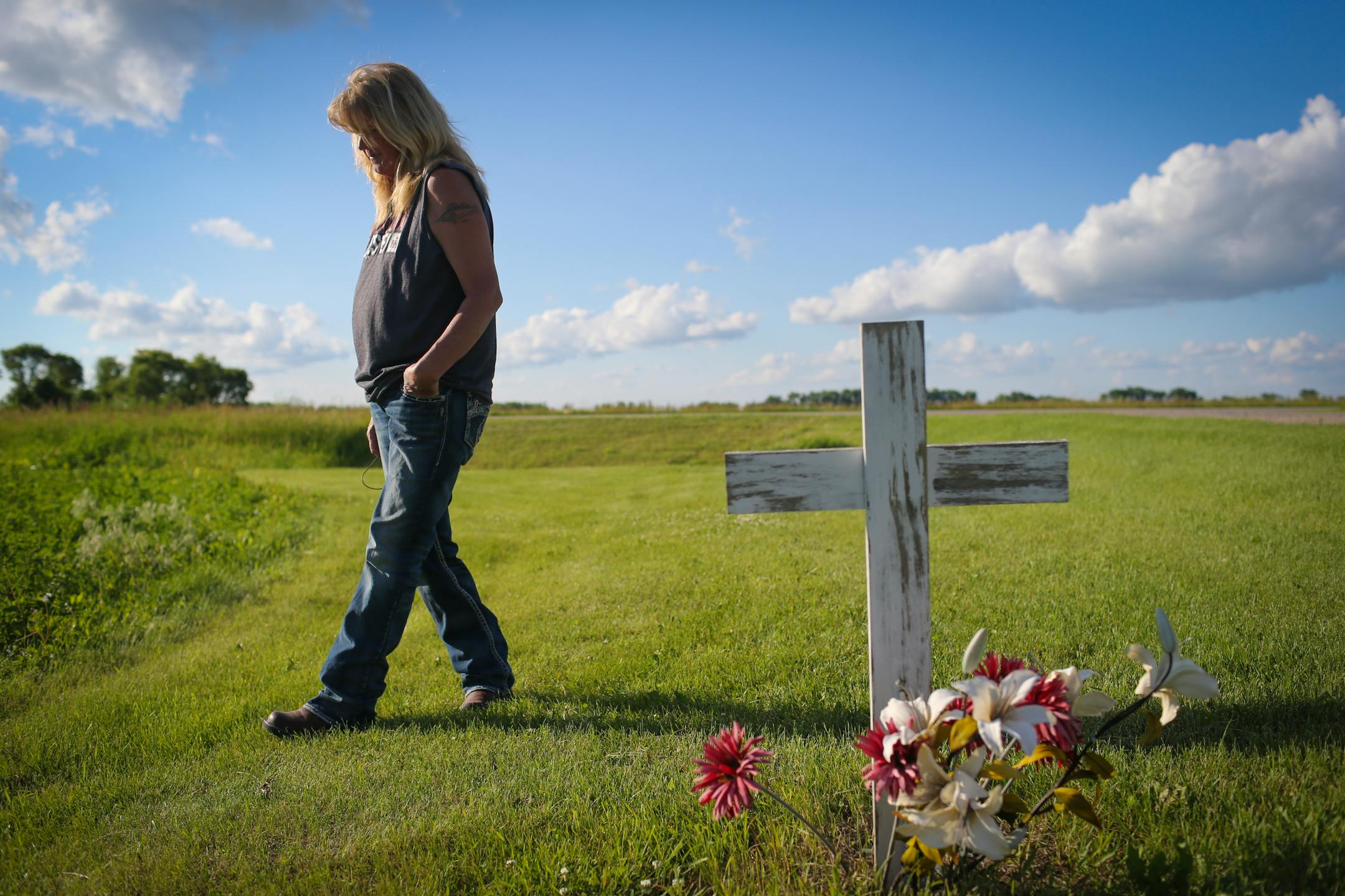 Gayle Lund walk by a cross she put in the spot of her driveway where her 24-year-old son Jake Fuglie died in a tractor rollover in 2010. Photographed on Monday, June 22, 2015, in Ulen, Minn. Fugally was driving his grandfather's old tractor to plow snow and it tipped on the small incline of the grass by the driveway. ] RENEE JONES SCHNEIDER � reneejones@startribune.com