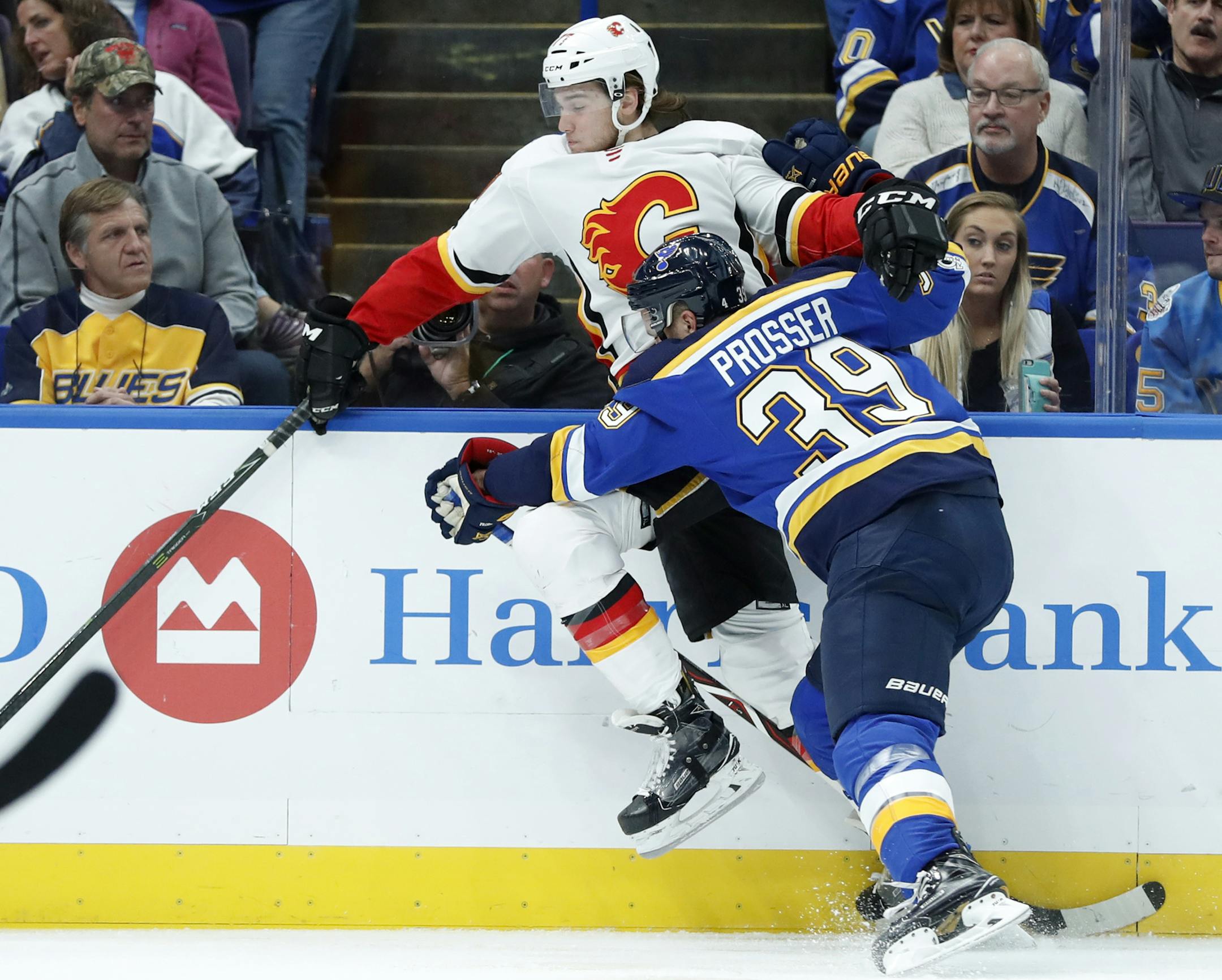 Calgary Flames' Mark Jankowski, left, reaches for the puck as he is checked by St. Louis Blues' Nate Prosser (39) during the first period of an NHL hockey game Wednesday, Oct. 25, 2017, in St. Louis. (AP Photo/Jeff Roberson)