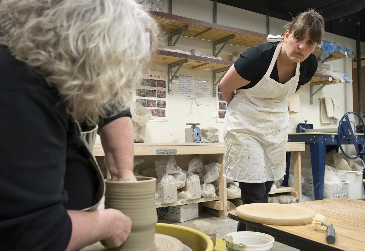 Instructor JoAnne Andres, left, demonstrates how to form texture using a pottery wheel as student Kari Khalil, of St. Paul, watches closely on Thursday night. ] (Aaron Lavinsky | StarTribune) Students at the Lakeville Area Arts Center take a pottery class under the tutelage of instructor JoAnne Andres on Friday, Jan. 9, 2015. The course is six weeks long and provides instruction and hands-on demonstration to students hoping to learn how to hand form and wheel throw pottery.