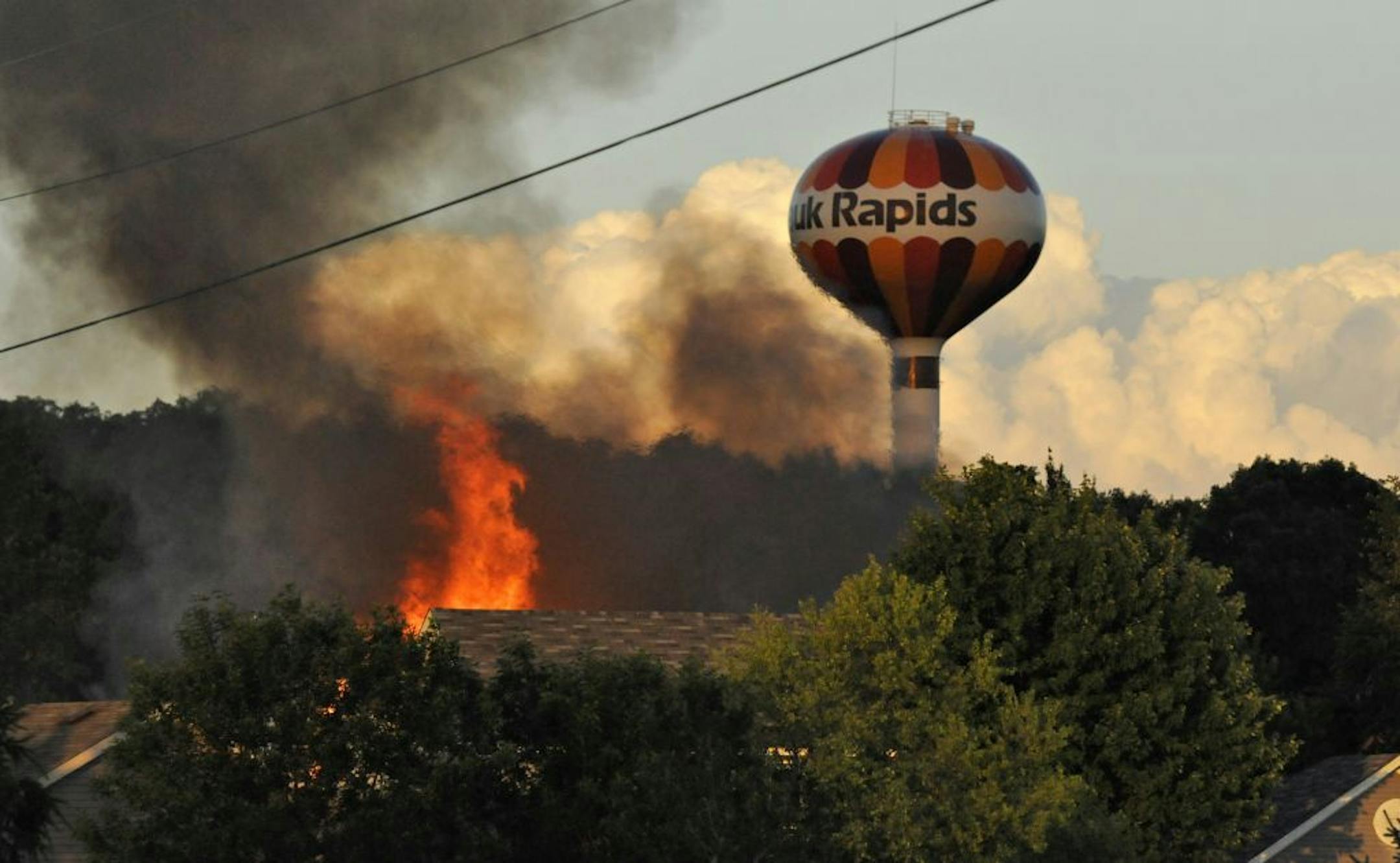Flames could be seen over the tree tops after a small plane crashed into a home at 731 Garden Place, killing the pilot and passenger and setting the home ablaze, in Sauk Rapids, Minn., Friday, June 20, 2014. No one else was hurt.