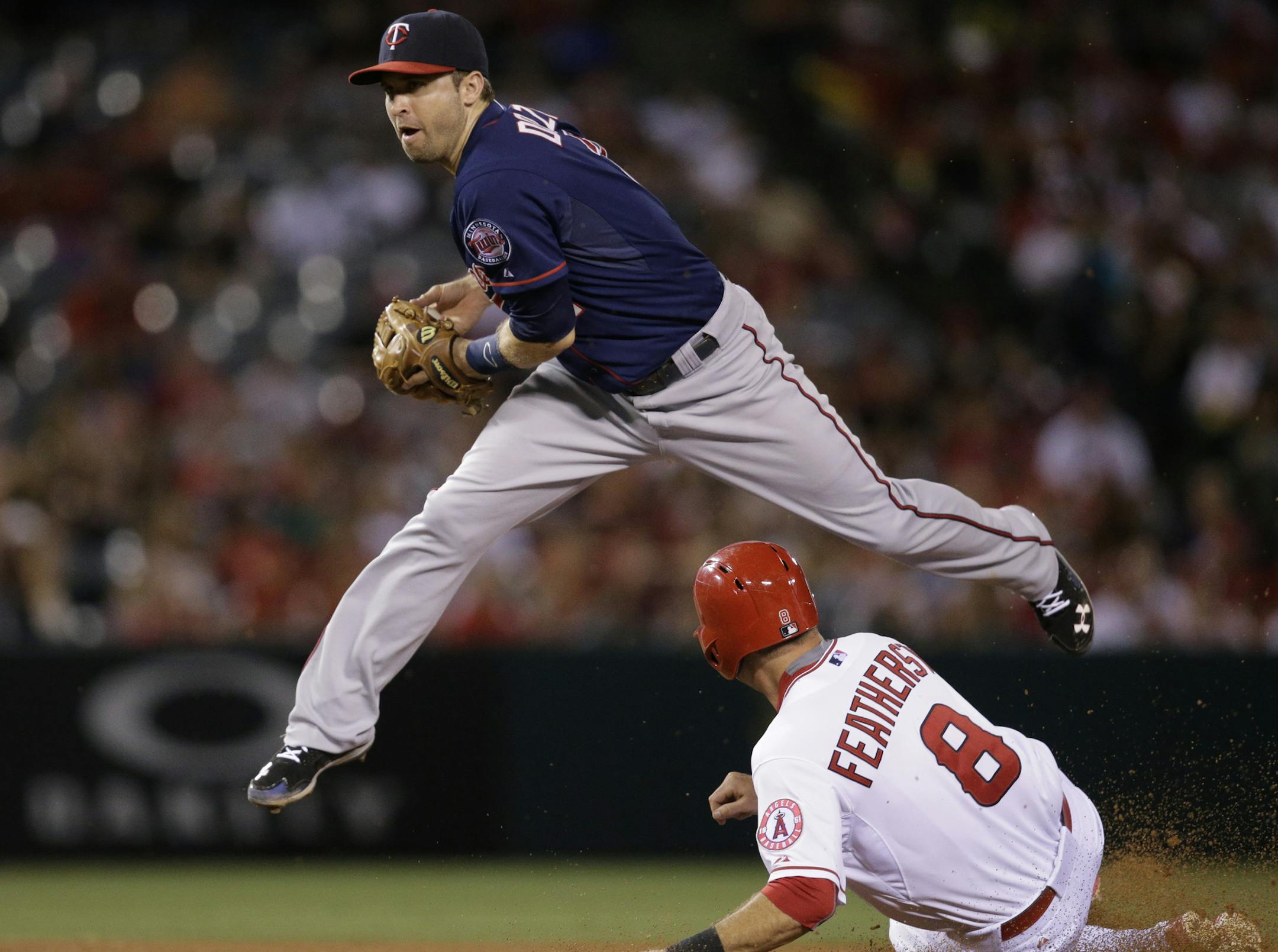 Minnesota Twins second baseman Brian Dozier looks to throw to first base after forcing out Los Angeles Angels' Taylor Featherston during the fourth inning of a baseball game, Wednesday, July 22, 2015, in Anaheim, Calif. Chris Iannetta was safe at first. (AP Photo/Jae C. Hong)