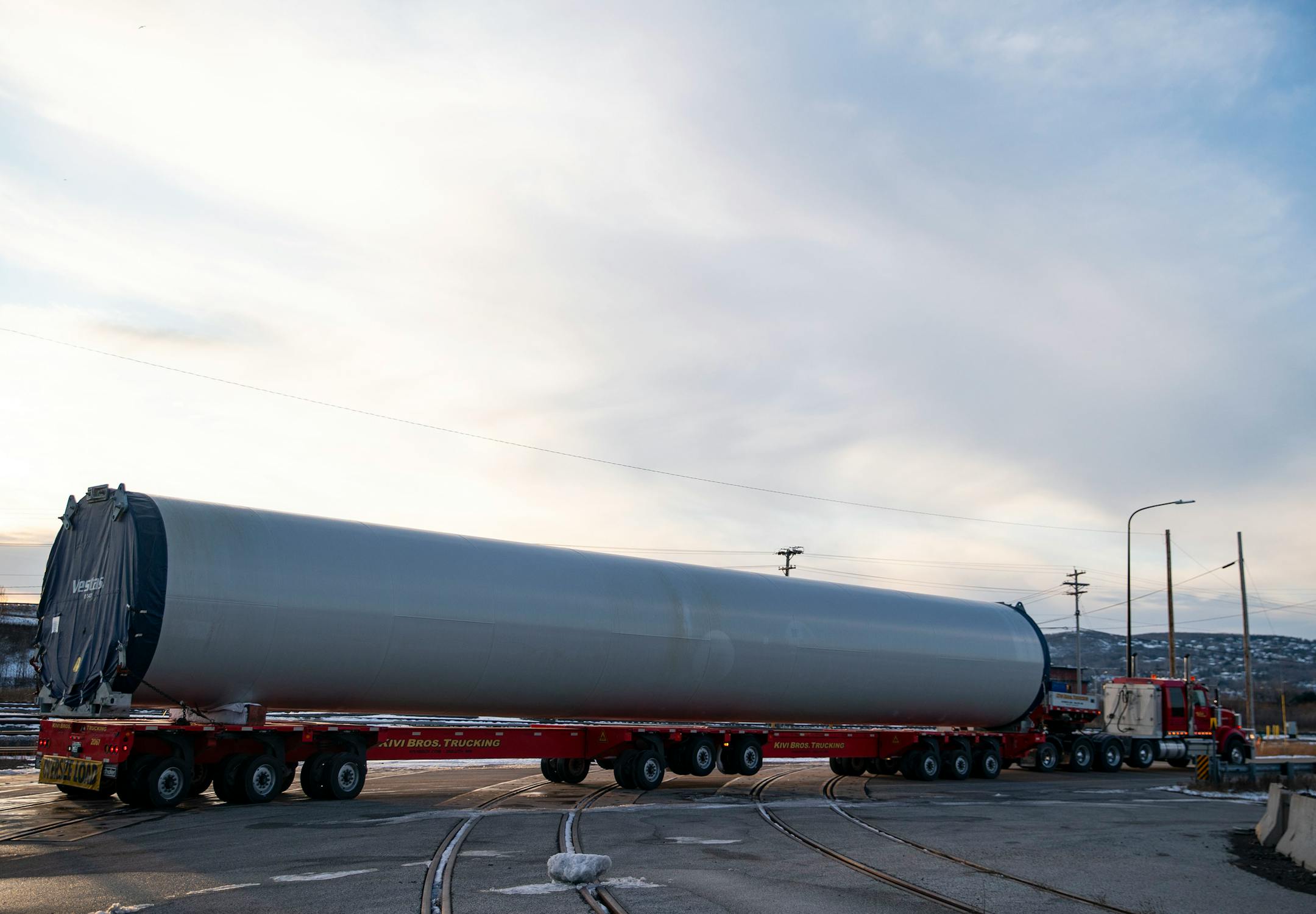 A flatbed truck transported a piece of wind turbine tower from the shipping docks to a storage field next door.