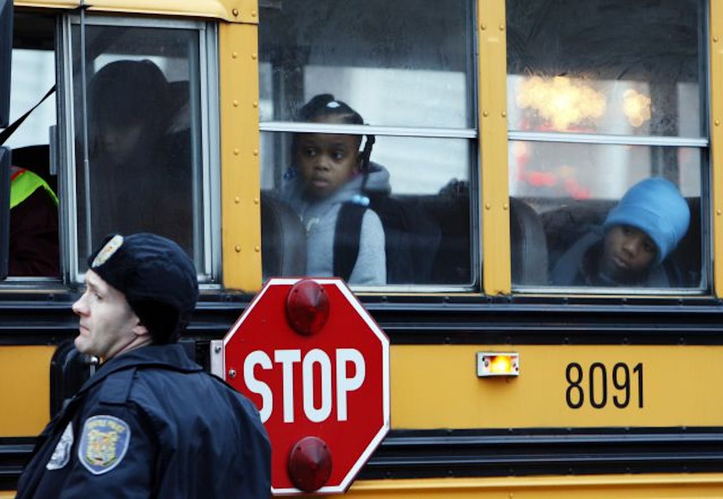 Schoolchildren look out the school bus window as a Seattle police officer explains the school is closed and the street is blocked because the suspect in the killing of four Lakewood, Wash. police officers is still at large in Seattle, on Monday, Nov. 30, 2009. A heavily armed SWAT team stormed a Seattle home Monday where they thought they had cornered the suspect in the slaying of four police officers at a coffee shop, only to find out that he was not in the house and still on the loose.