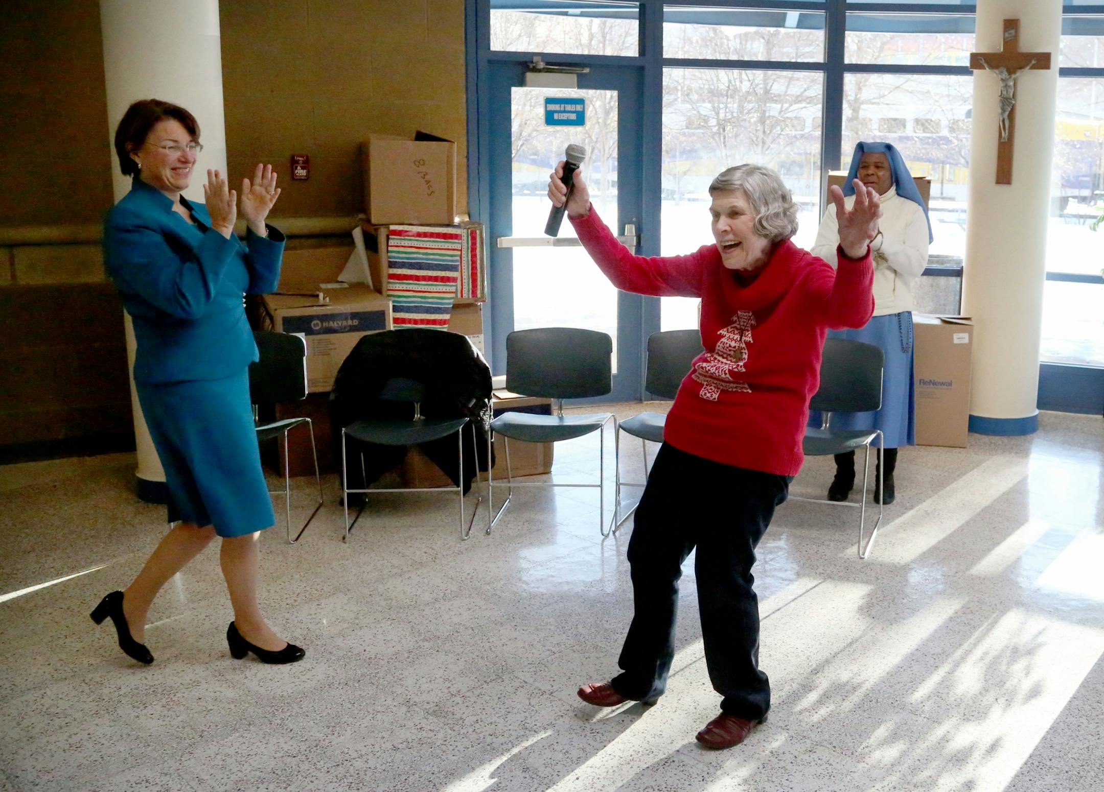 Sen. Amy Klobuchar reacts next to Mary Jo Copeland at Mary's Place to show and discuss a fifth grader's recent project and offer Christmas cheer in 2016.