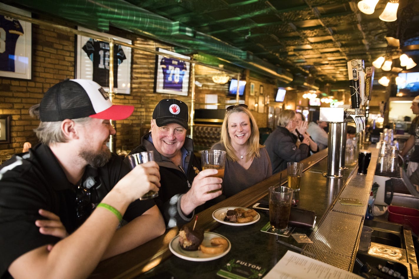 O'Gara's regulars Joe Shea, from left, and Patrick Lynch clink glasses as Sara Clemetson looks on at the bar. Shea has been coming to O'Gara's with his family since he was a child. Lynch, also known as "Chopper" worked at O'Gara's for 12 years about 20 years ago.