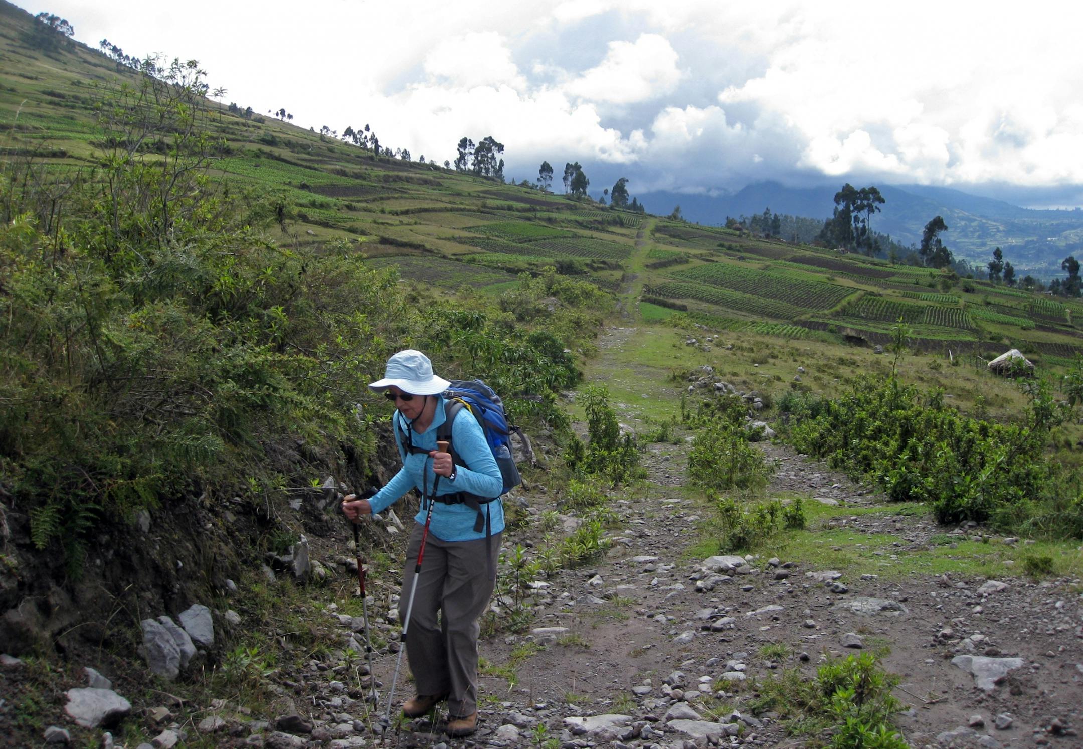 Mary Jo George of Asheville, N.C., hikes between patches of corn and fava beans fields near San Pablo Lake in the Highlands of Ecuador.