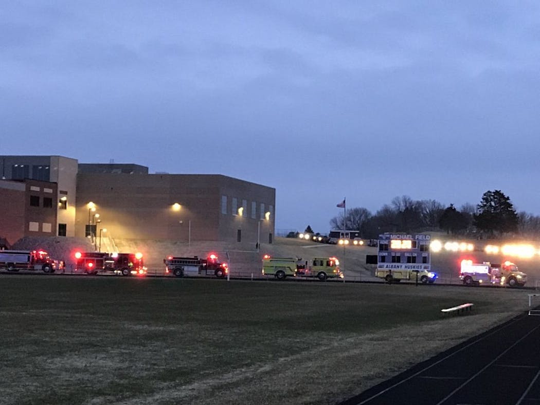 Cars and emergency vehicles surrounded Michael Field at Albany High School, which was lit up as part of #BethelightMN during COVID-19 pandemic.