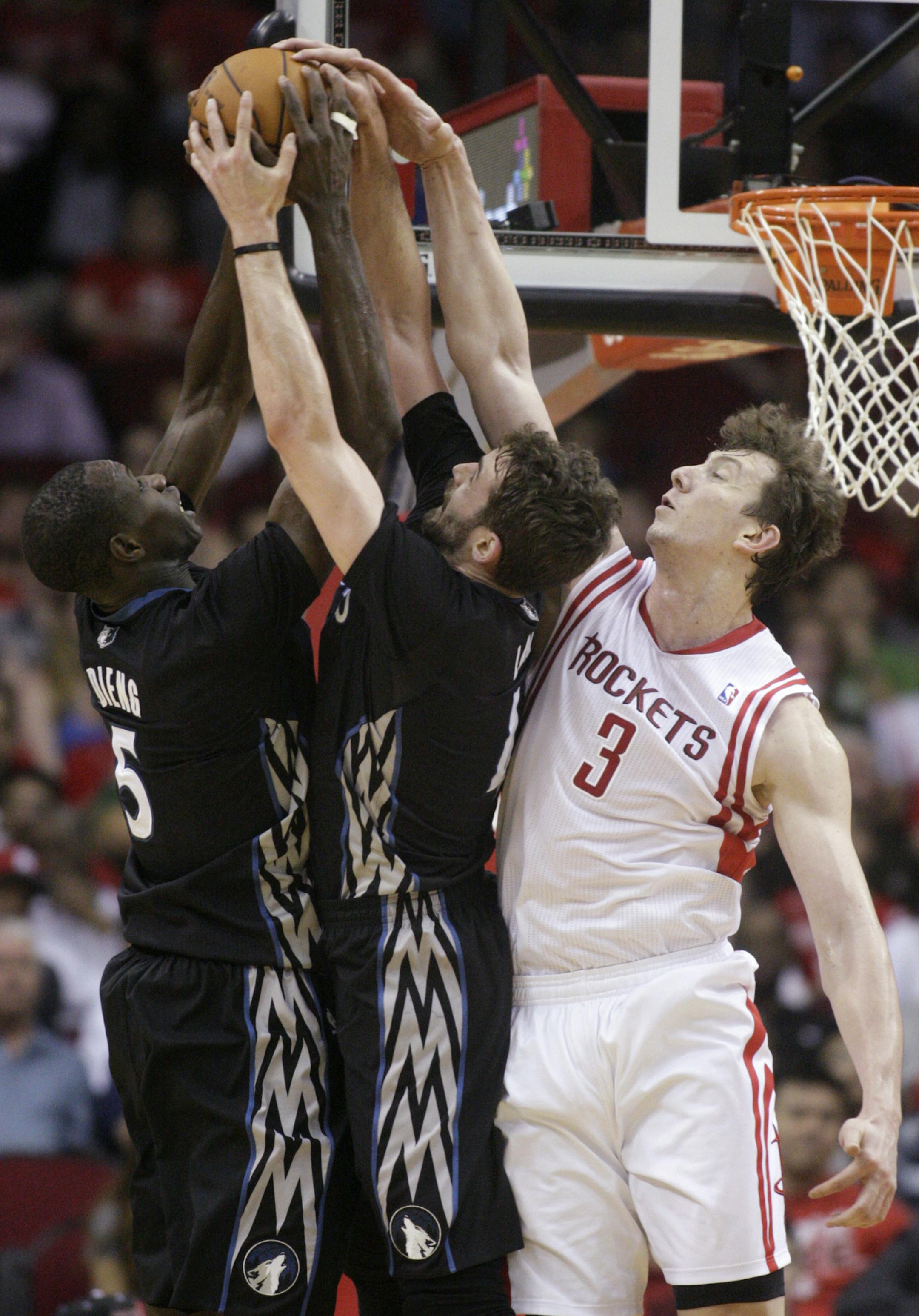 Minnesota Timberwolves' Gorgui Dieng (5) and Kevin Love bring down a rebound against Houston Rockets' Omer Asik (3) during the second quarter of an NBA basketball game, Thursday, March 20, 2014, in Houston. (AP Photo/Patric Schneider)