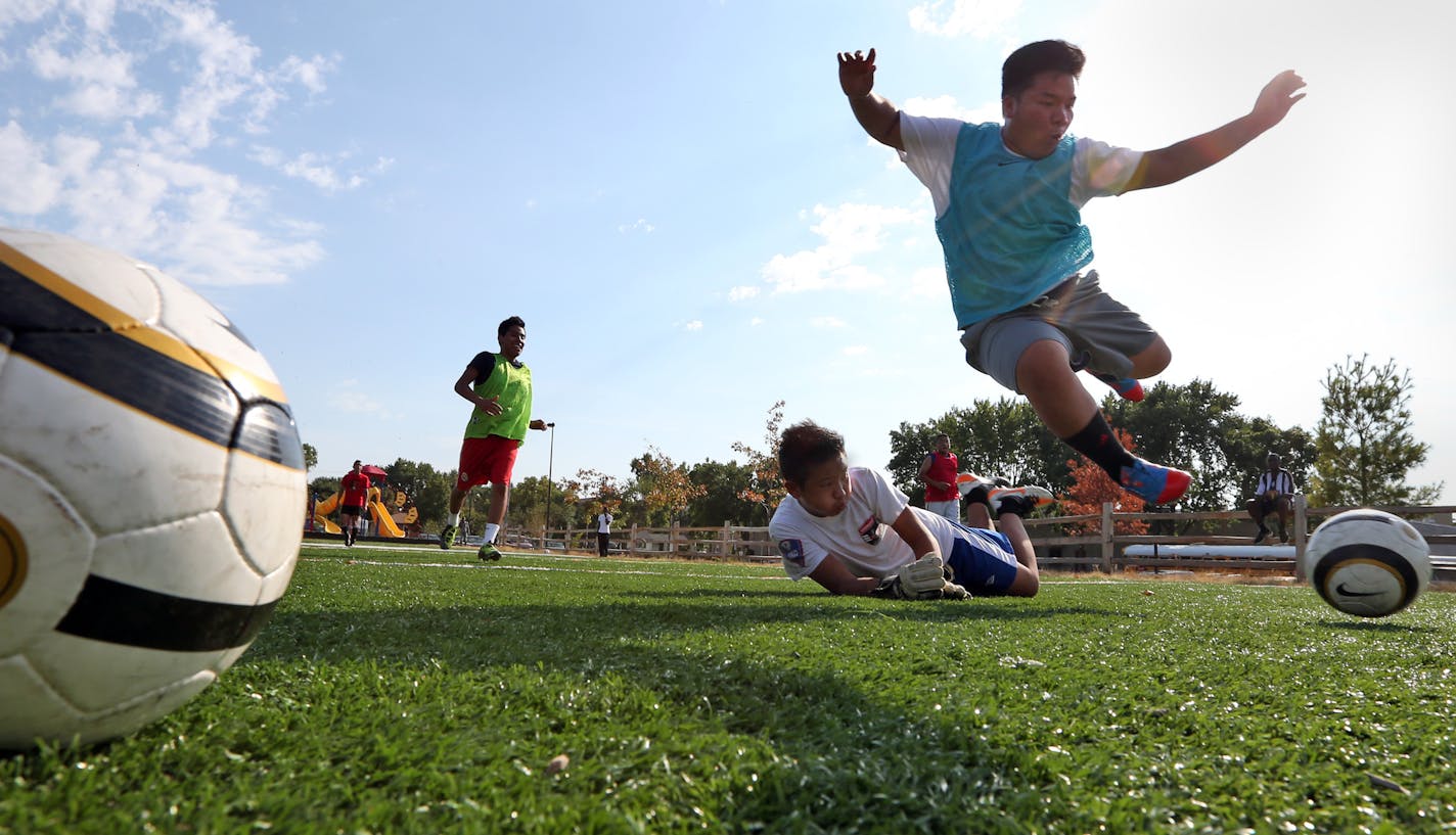 Prairie Seeds Academy goalie Sunny Vang made a sliding save on Johnny Moua at practice. The Lycans feature players native to Guinea, Liberia, Cameroon and other countries.