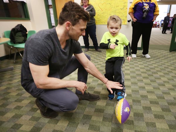 Minnesota Vikings kicker Blair Walsh held a football for Max Birdwell (4) during a visit at Northpoint Elementary School Thursday.