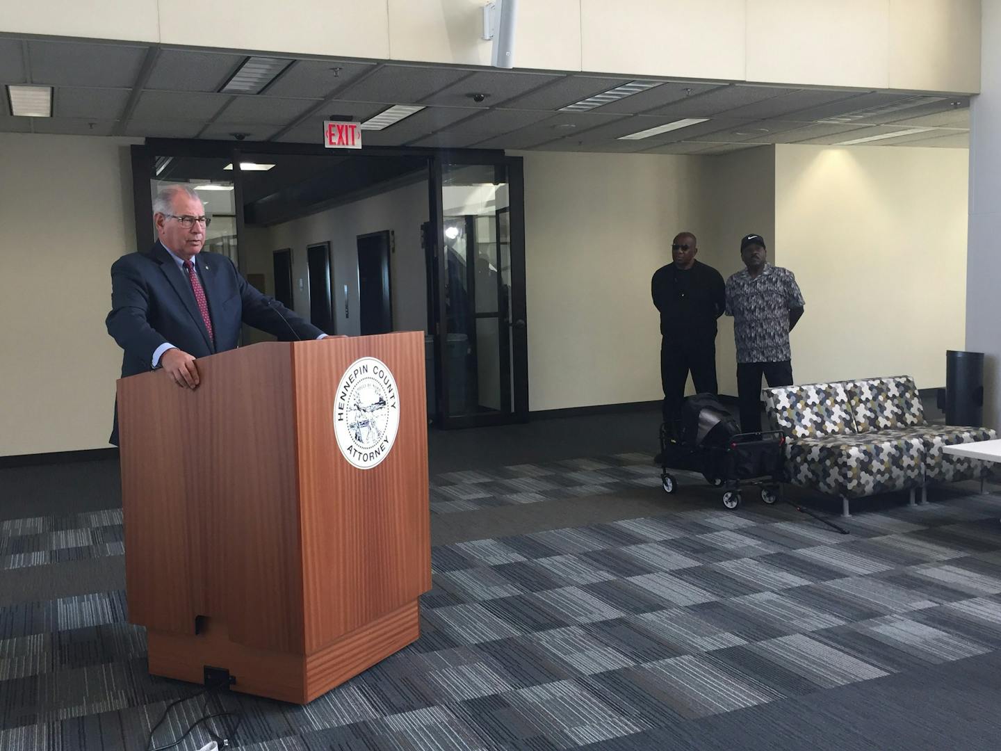 Hennepin County Attorney Mike Freeman speaks at a news conference while activstis Tyrone Terrill and Spike Moss watch.