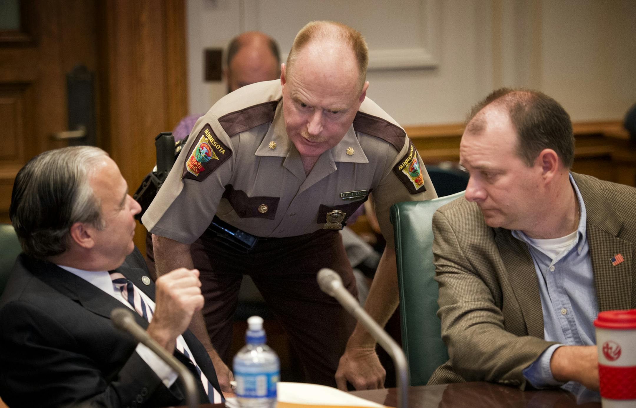 State Patrol Major Bob Meyerson talked with Rep. Michael Paymar, DFL-St. Paul, and Rep. Kelby Woodard, R-Belle Plaine, before the hearing.