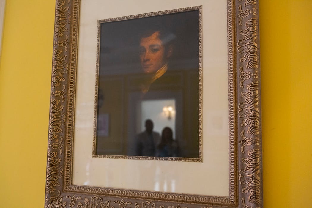 Jamie and Frantz Arty are reflected in a portrait of the original homeowner, William Townsend McCoun, a prominent New York abolitionist and judge, who lived in the mansion until his death in 1878.