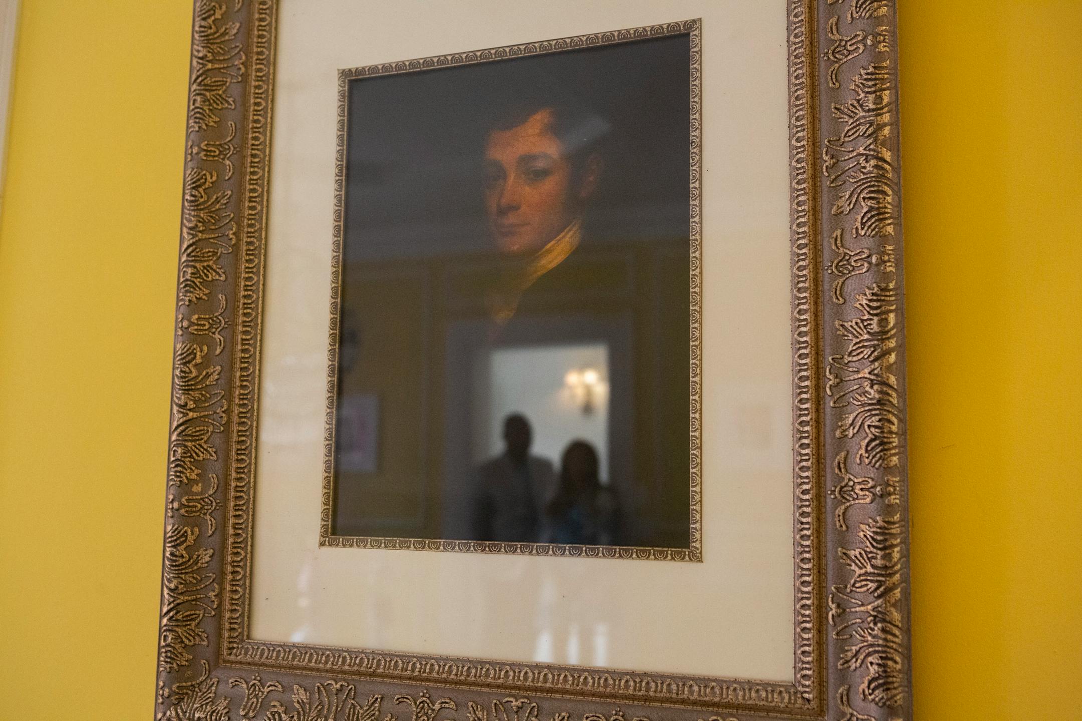 Jamie and Frantz Arty are reflected in a portrait of the original homeowner, William Townsend McCoun, a prominent New York abolitionist and judge, who lived in the mansion until his death in 1878. in Photographed July 9, 2021, in Oyster Bay, N.Y. MUST CREDIT: Photo for The Washington Post by Calla Kessler