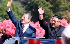 South Korean President Moon Jae-in, left, and North Korean leader Kim Jong-un wave from a car during a parade through a street in Pyongyang, North Kor