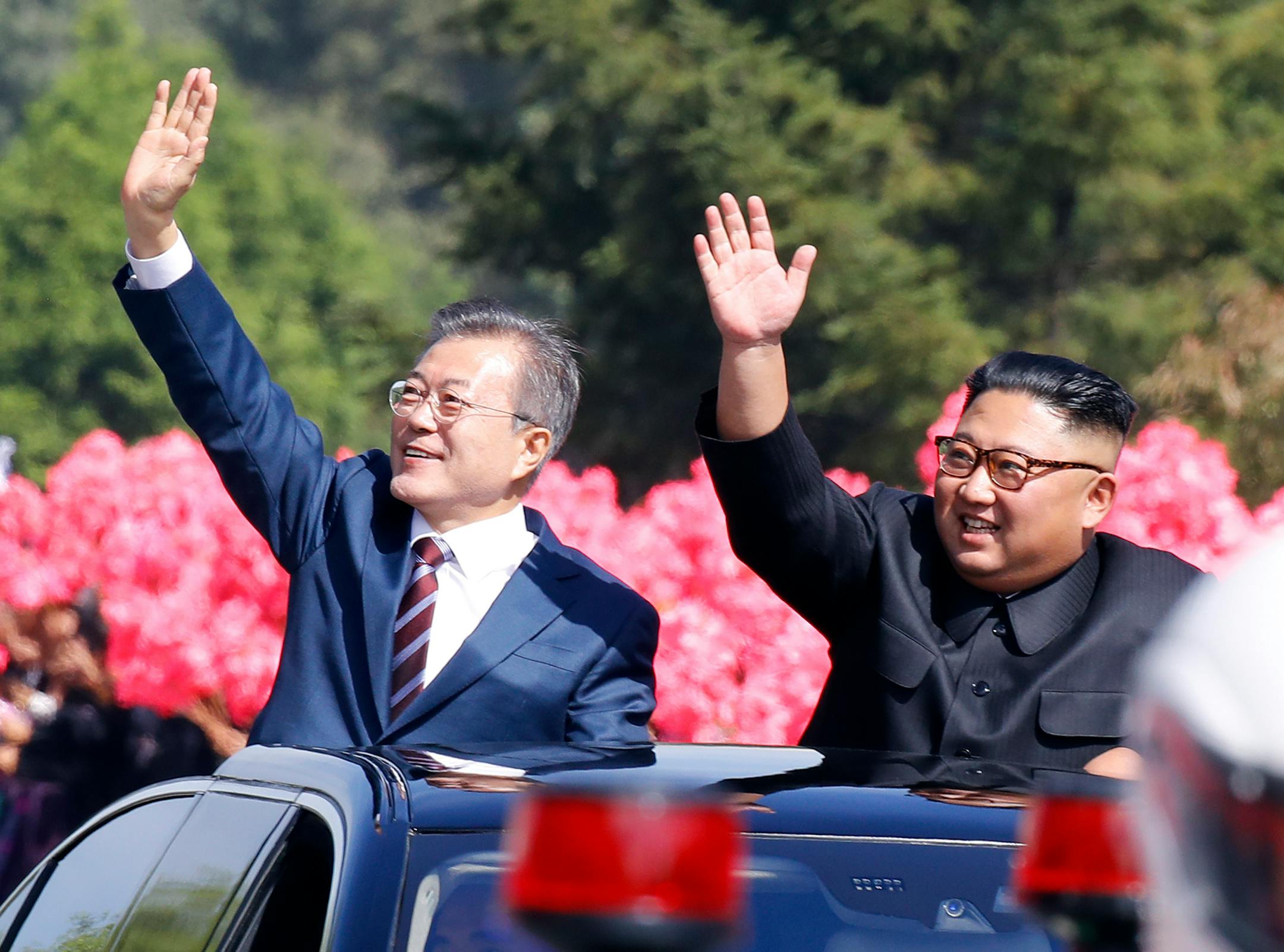 South Korean President Moon Jae-in, left, and North Korean leader Kim Jong-un wave from a car during a parade through a street in Pyongyang, North Korea, Tuesday, Sept. 18, 2018.