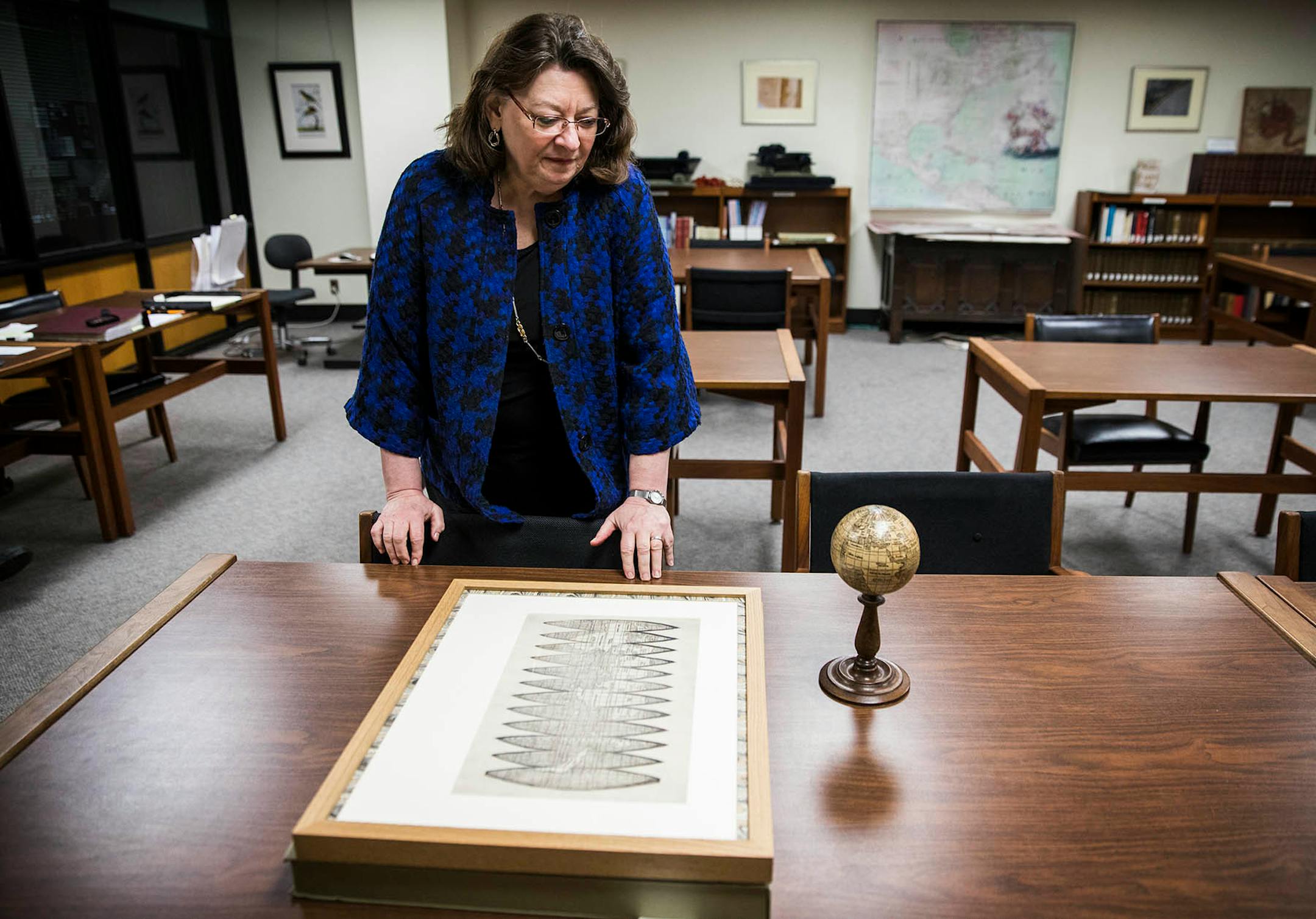Marguerite Ragnow, curator of the James Ford Bell Library, stands over the globe gores map and a replica that has been put onto a three inch globe.