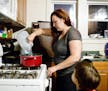 Lee Walters empties a bottle of store-bought drinking water into a pot to make pasta for dinner while her son Gavin, 4, watches at her home in Flint, 
