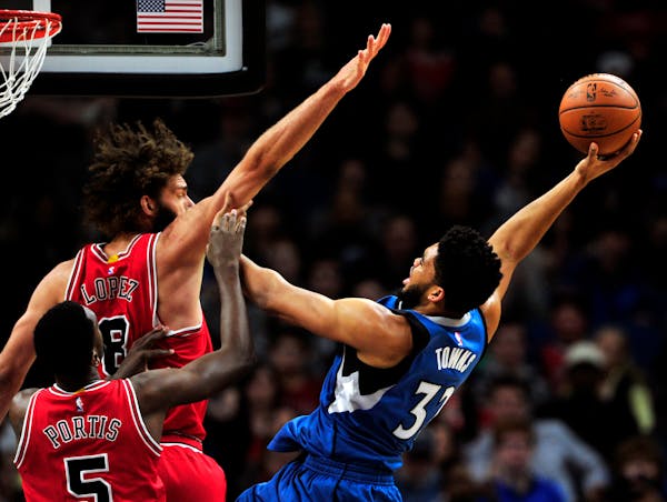 Minnesota Timberwolves center Karl-Anthony Towns (32) shoots against Chicago Bulls' Bobby Portis (5) and Robin Lopez (8) during the first quarter of a