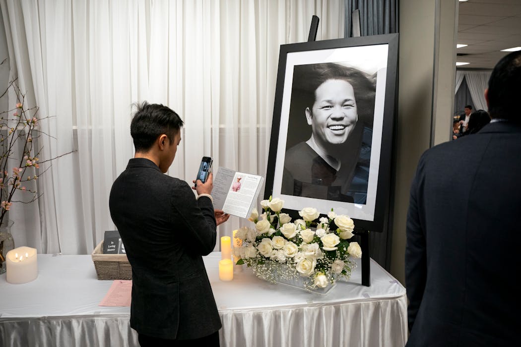 One of Tou Ger Xiong’s friends took a photo of his funeral brochure in front of Xiong’s headshot at the memorial service on Saturday in St. Paul.