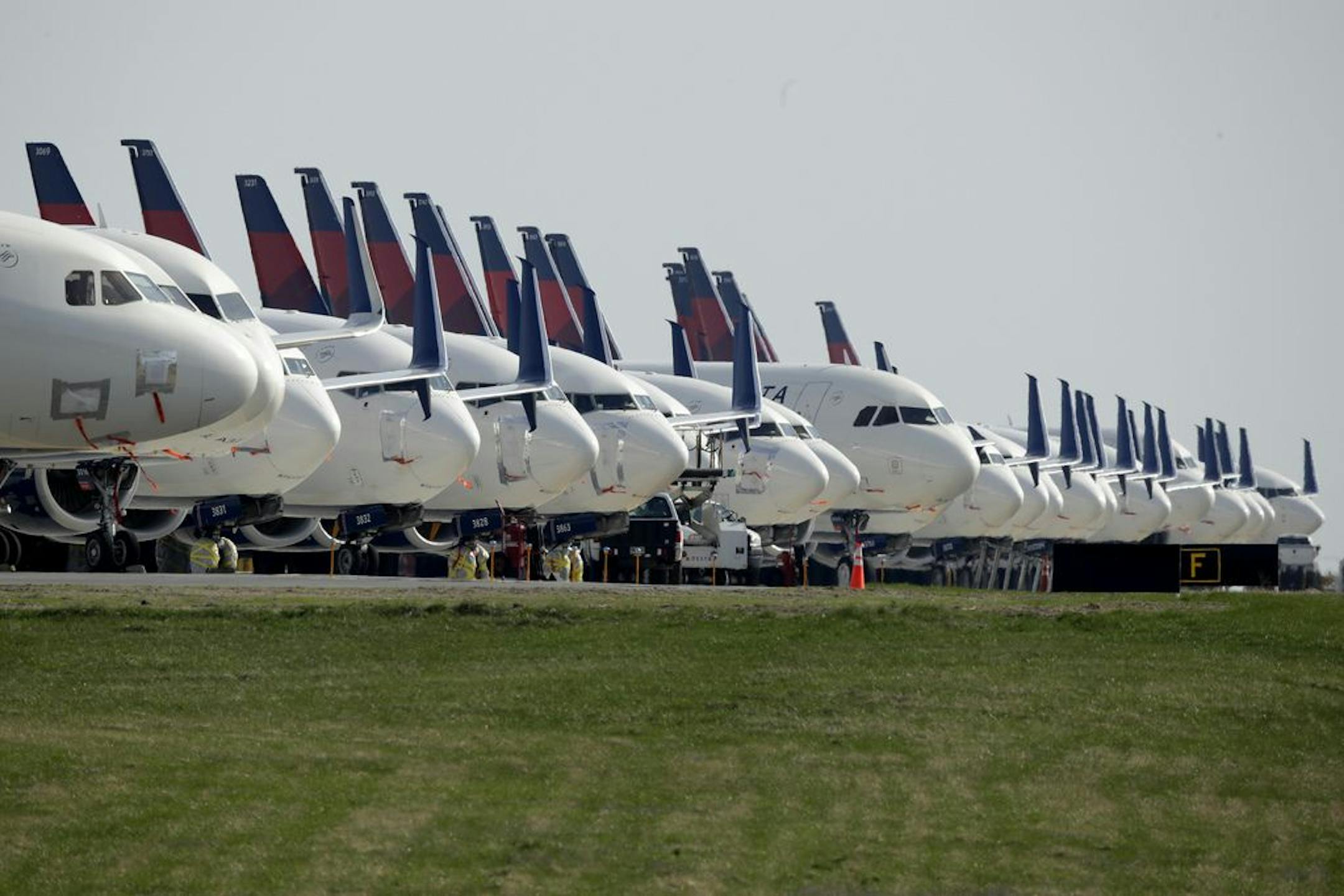 FILE - In this April 1, 2020, file photo, several dozen mothballed Delta Air Lines jets are parked at Kansas City International Airport in Kansas City, Mo. The number of Americans getting on airplanes has sunk to a level not seen in more than 60 years as people shelter in their homes to avoid catching or spreading the new coronavirus. The Transportation Security Administration screened fewer than 100,000 people on Tuesday, April 7, a drop of 95% from a year ago.