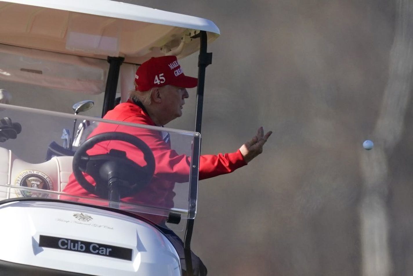 President Donald Trump tosses a golf ball as he plays golf at Trump National Golf Club, on Thanksgiving, Thursday, Nov. 26, 2020, in Sterling, Va.