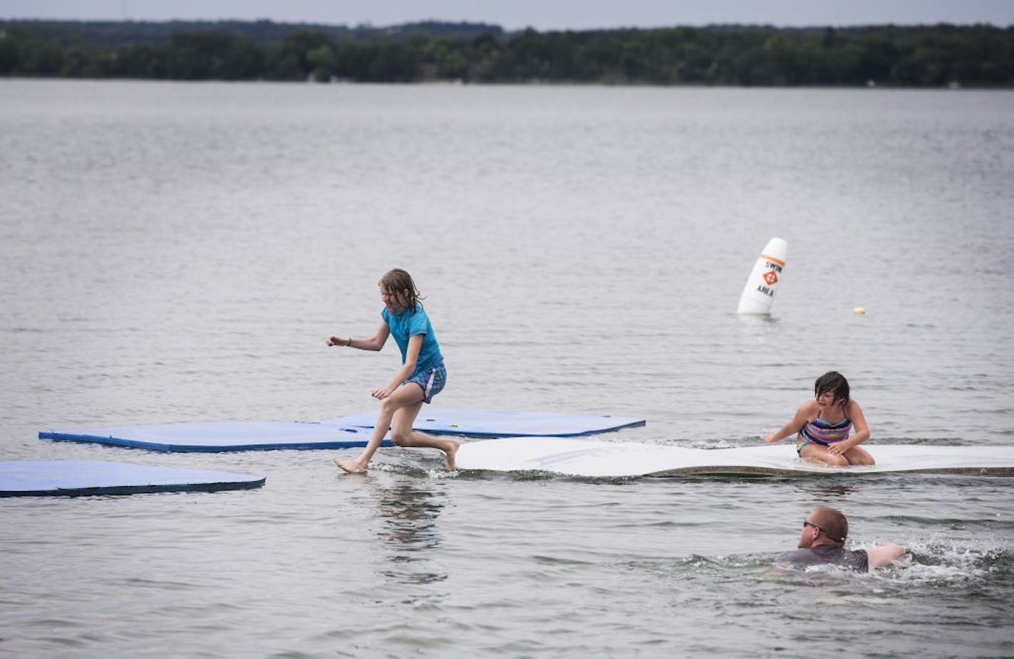 Kay Smith, from left, 11, her sister Kallie, 8, and father Travis Smith swim in Lake Minnewaska in Glenwood on Wednesday, July 8, 2015.