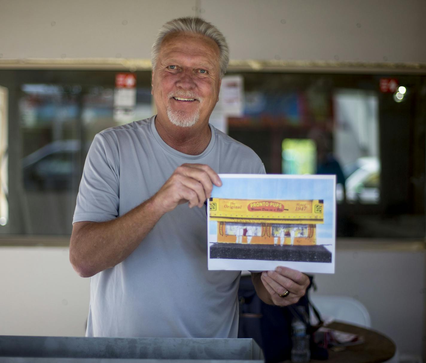 Owner Gregg Karnis poses for a portrait with a piece of concept art for the new Pronto Pups stand. ] ALEX KORMANN &#x2022; alex.kormann@startribune.com Pronto Pups has been a staple at the state fair since 1947 when they introduced the first fair food on a stick. When they first opened, the original pronto pup was only 10 cents. They have moved from building to building over the years and this year they are constructing a new stand, significantly larger than their last space. The owner, Gregg Ka