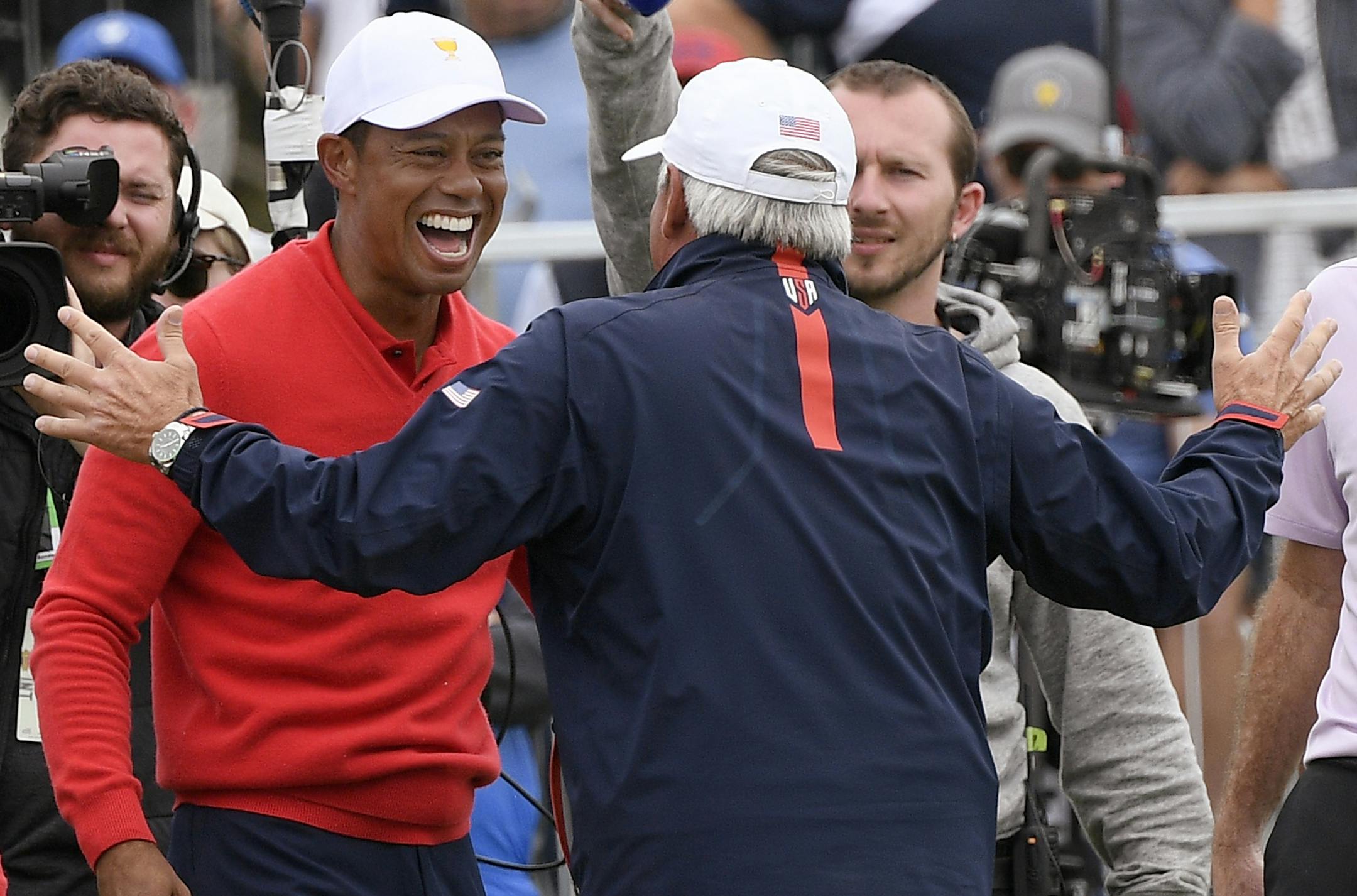 U.S. team player and captain Tiger Woods, left, celebrates with vice captain Fred Couples after Woods won his singles match during the President's Cup golf tournament at Royal Melbourne Golf Club in Melbourne, Sunday, Dec. 15, 2019. (AP Photo/Andy Brownbill)