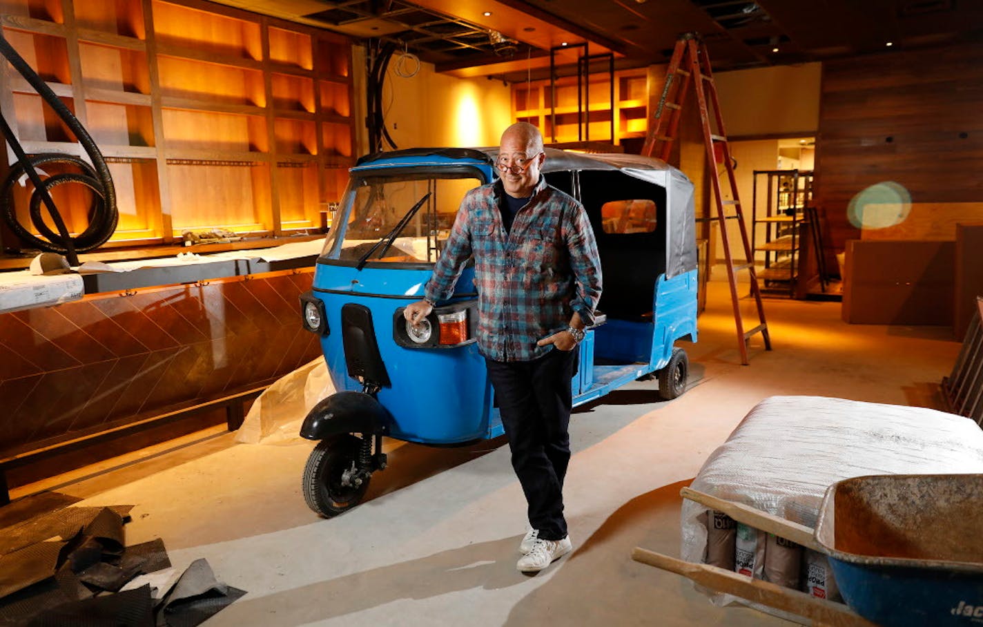 Chef Andrew Zimmern poses for a portrait with a tuk-tuk that will be part of decor inside his new restaurant Lucky Cricket.