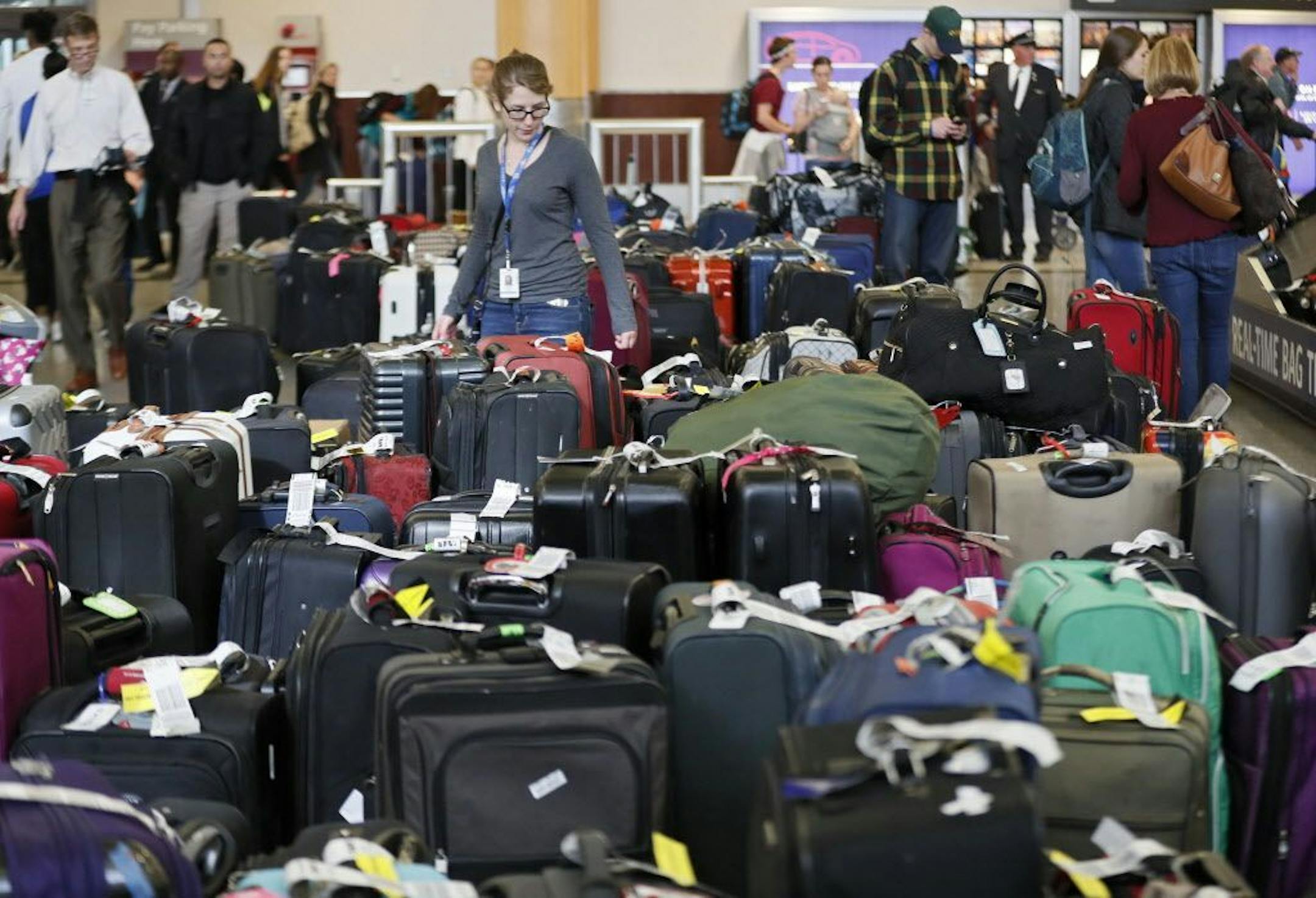 People look over luggage Monday, Dec. 18, 2017, at Hartsfield-Jackson International Airport in Atlanta. Power was restored at the airport after a massive outage Sunday afternoon that left planes and passengers stranded for hours, forced airlines to cancel more than 1,100 flights.