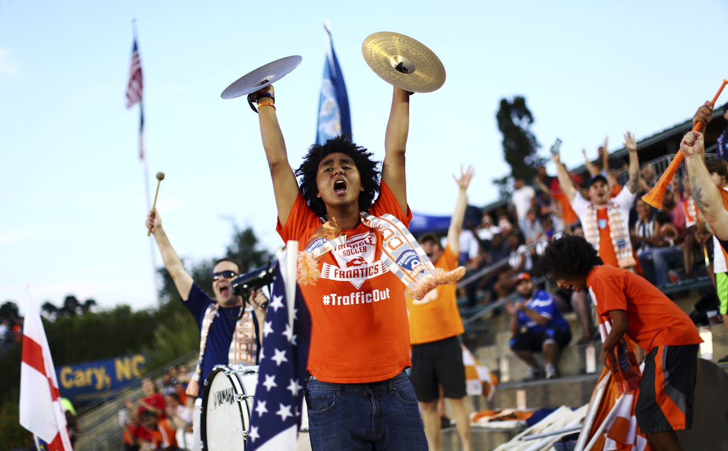 Carolina RailHawks fans, some wearing Traffic Out T-shirts, cheer during game against the New York Cosmos in Cary, N.C., Aug. 22, 2015. The RailHawks of the North American Soccer League face existential questions as a result of a crackdown on corruption at the sport&#xed;s highest levels. (Travis Dove/The New York Times)